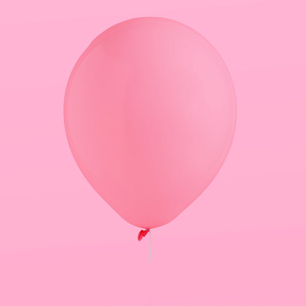 Single pink balloon against a pink background
