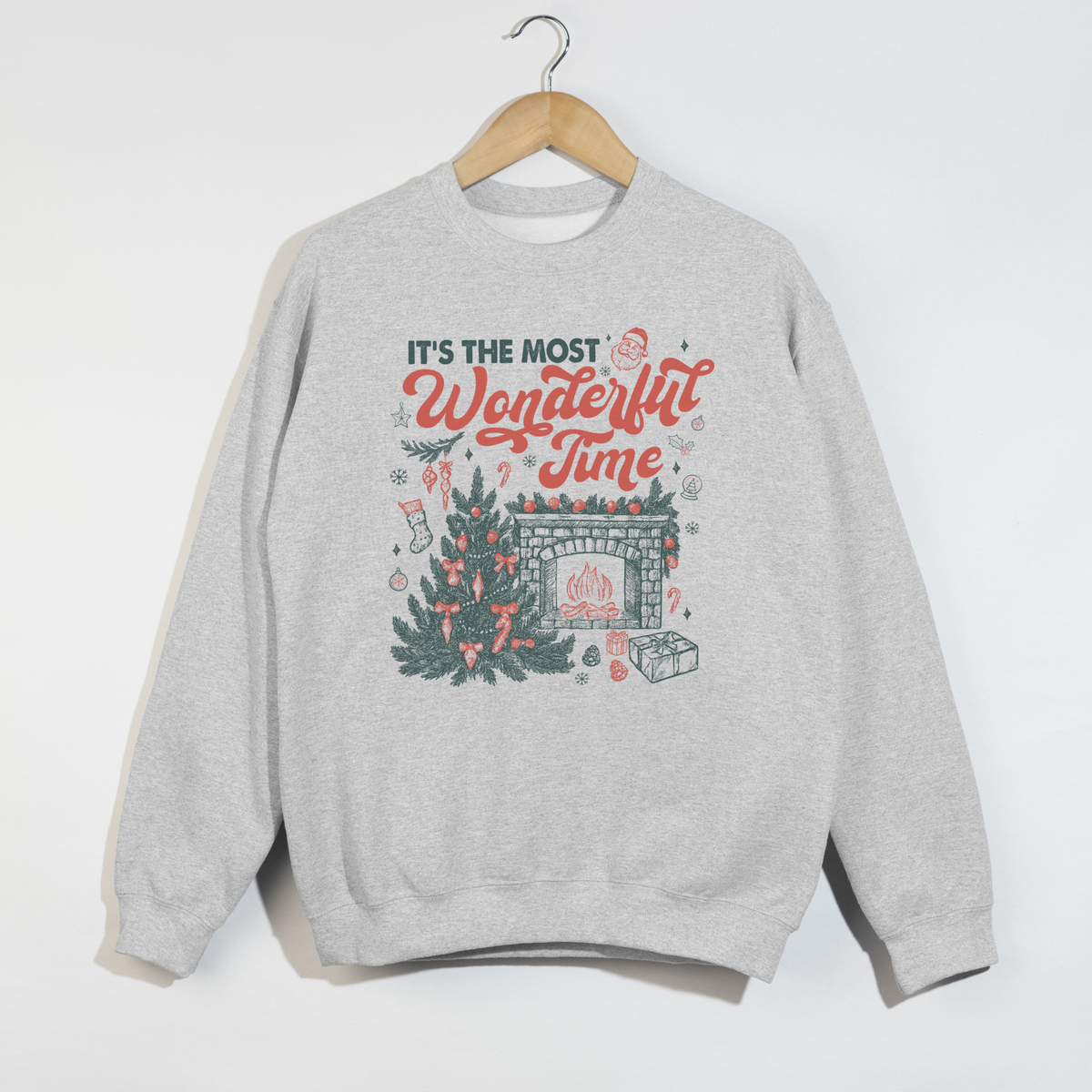 Ash gray crewneck sweatshirt featuring “It’s the Most Wonderful Time” holiday print with Christmas tree and fireplace graphic.