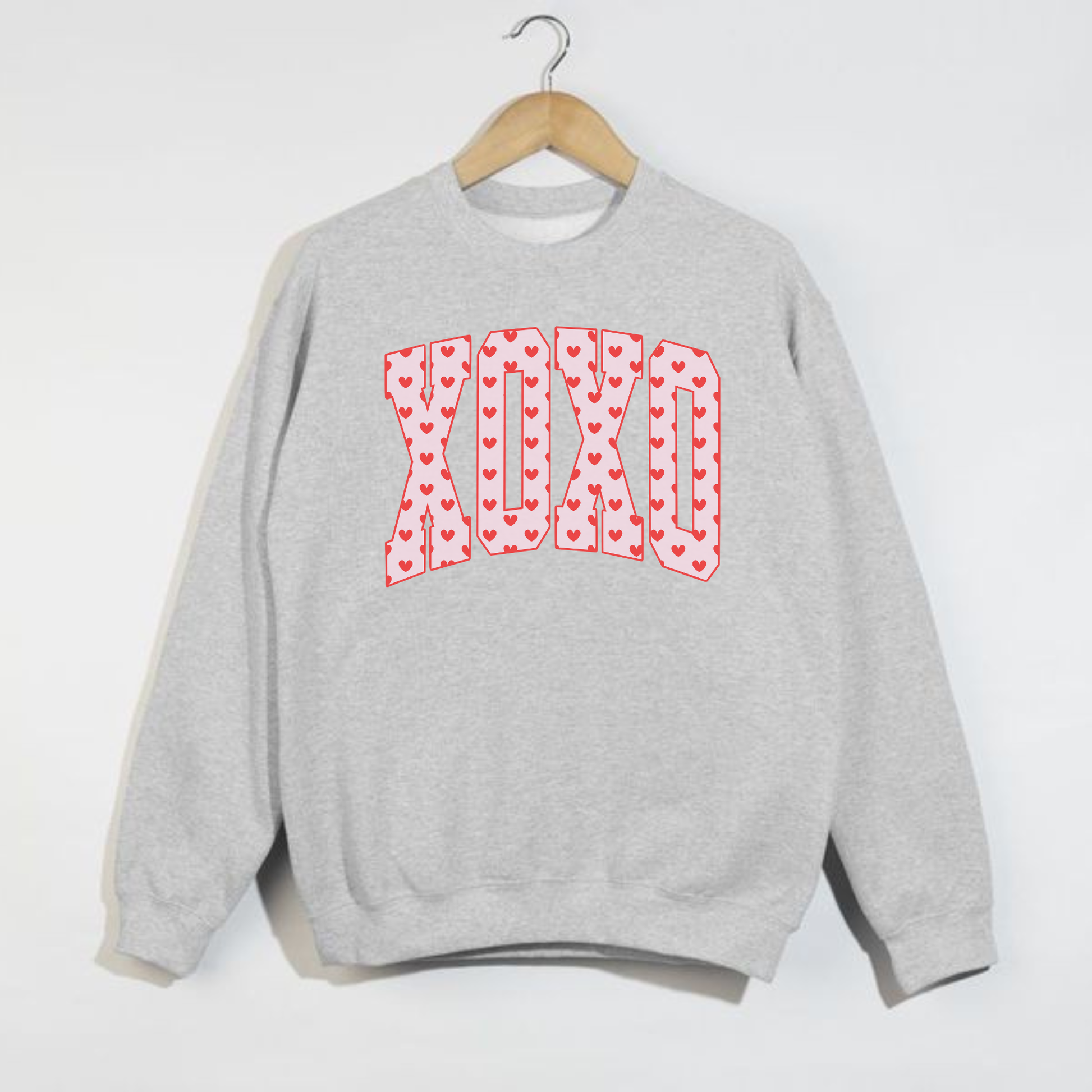 Grey Gildan crewneck sweatshirt with XO heart Valentine graphic hanging on hanger