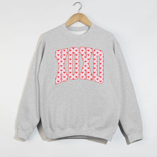 Grey Gildan crewneck sweatshirt with XO heart Valentine graphic hanging on hanger