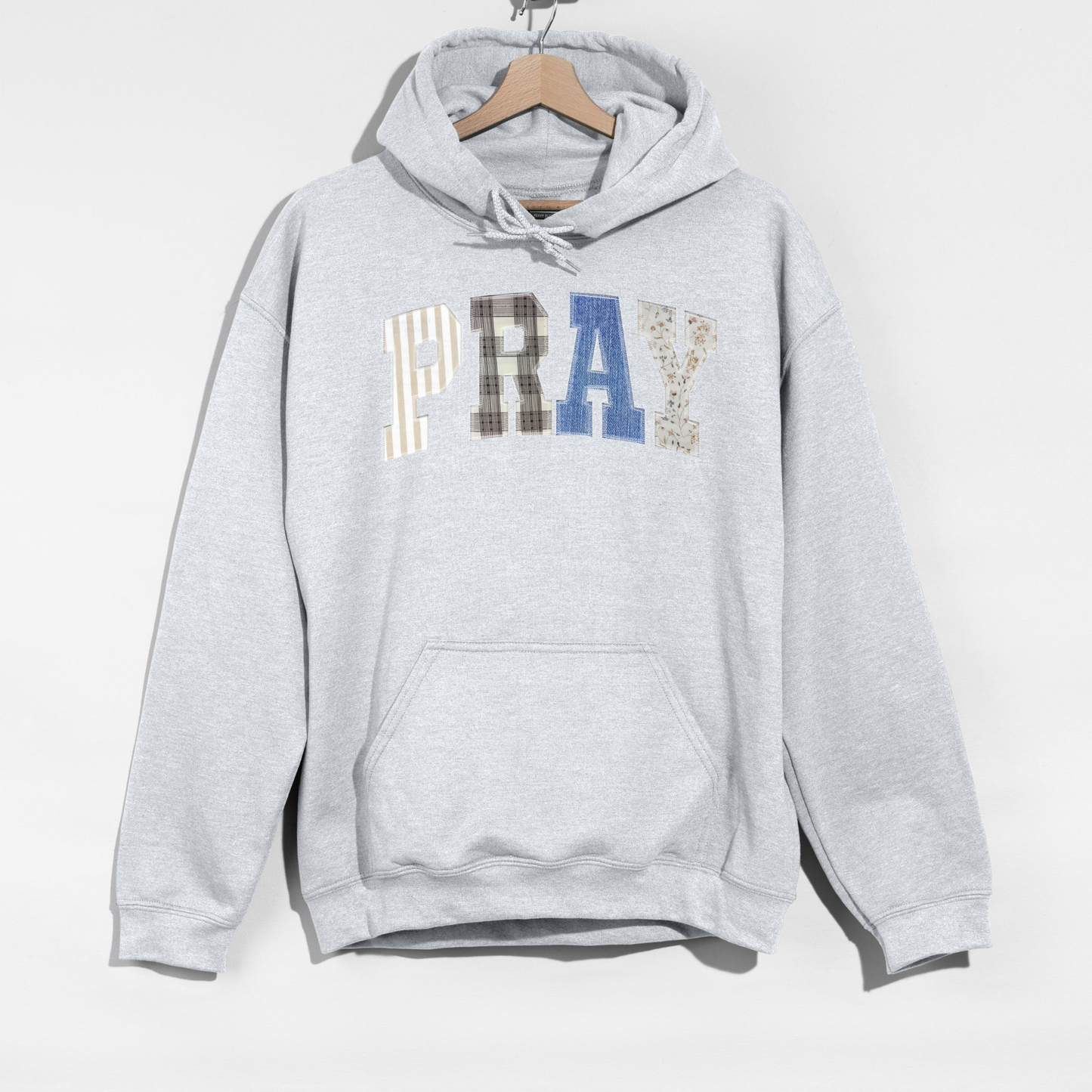 Close-up of PRAY applique lettering with mixed neutral patchwork textures