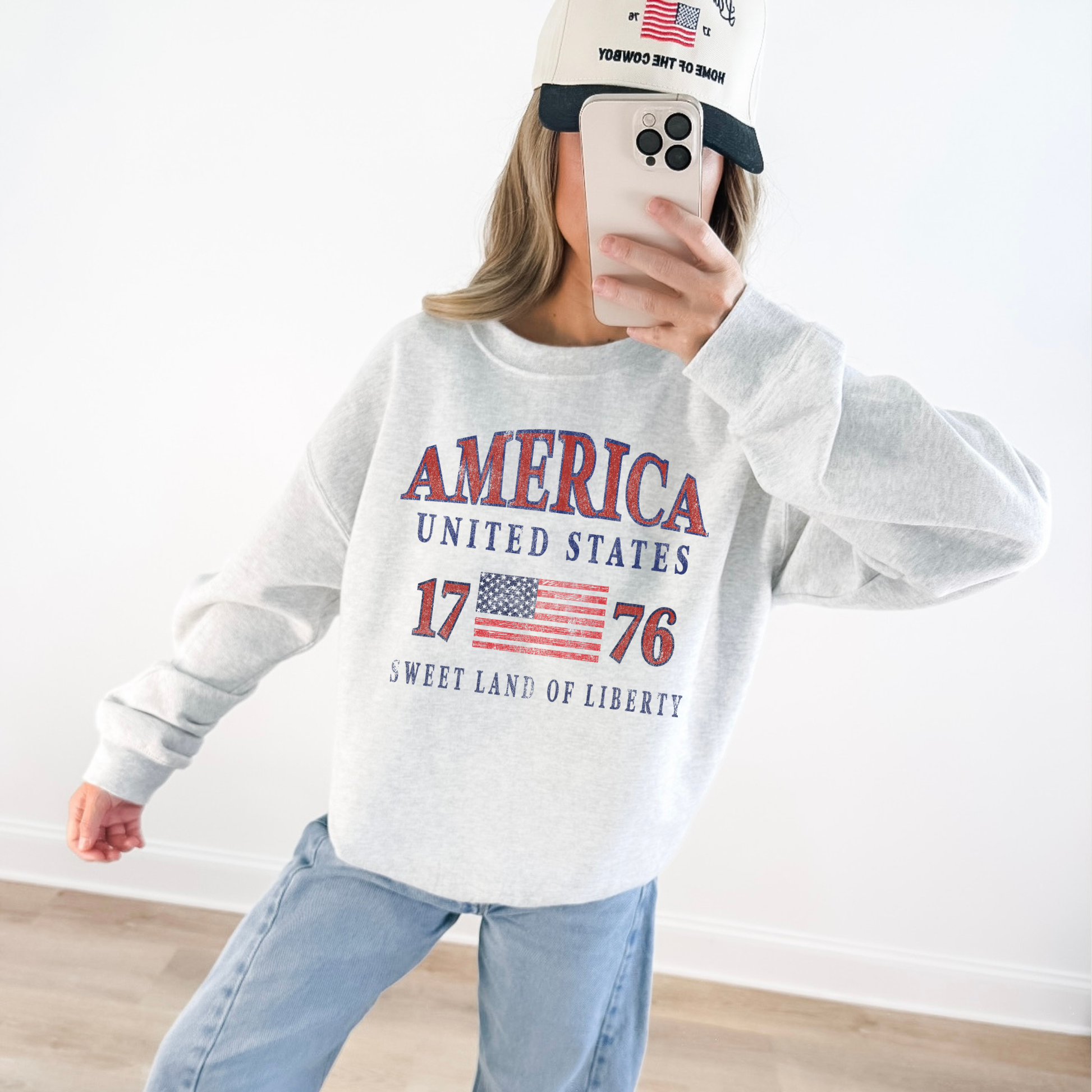 “Woman wearing America United States 1776 patriotic sweatshirt with red hat”