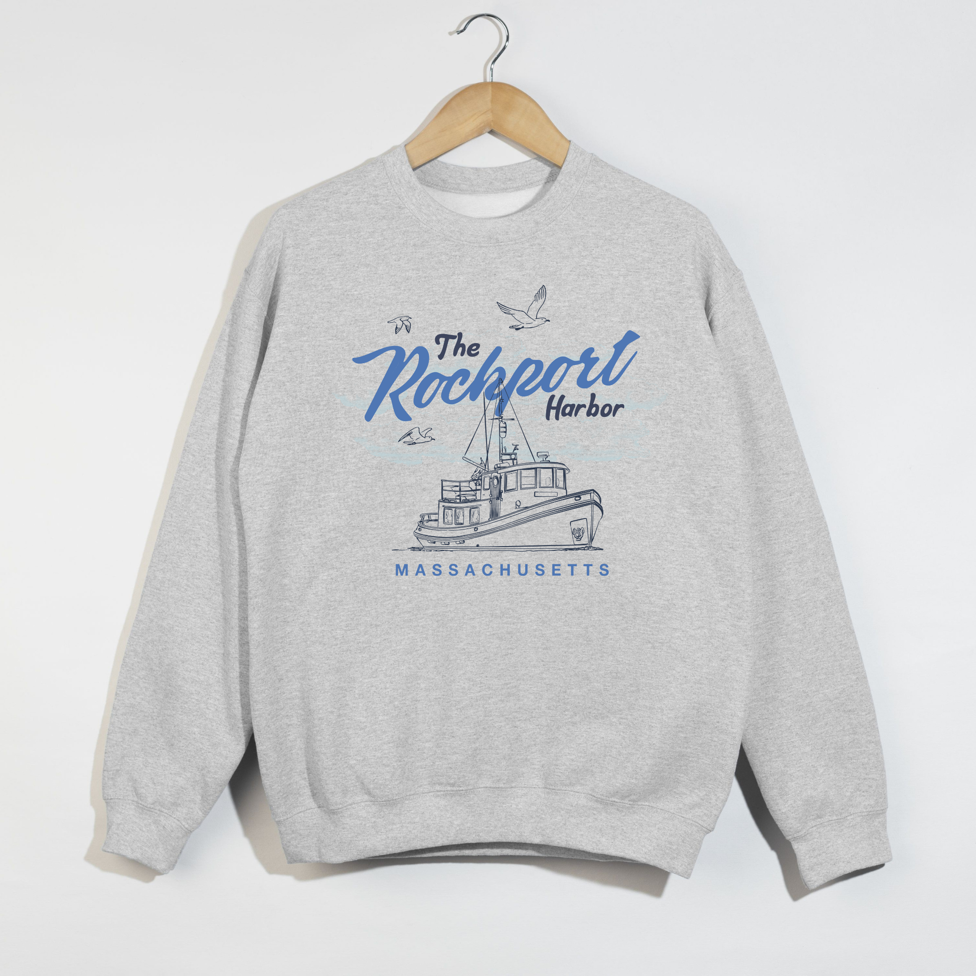 Gray sweatshirt with 'The Rockport Harbor, Massachusetts' design on a hanger against a white background