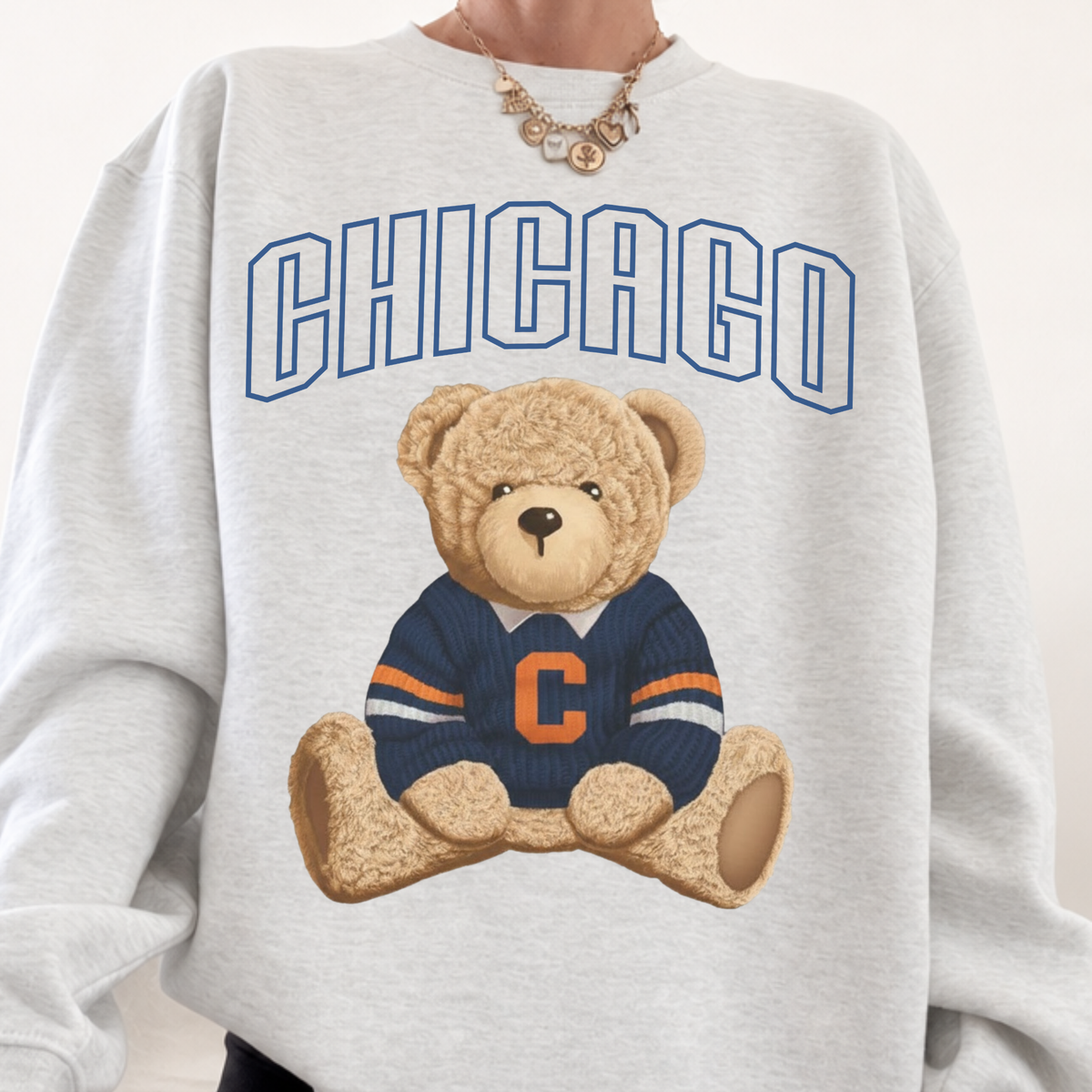 Close-up of ash grey Chicago football teddy bear sweatshirt with oversized varsity lettering and navy orange graphic