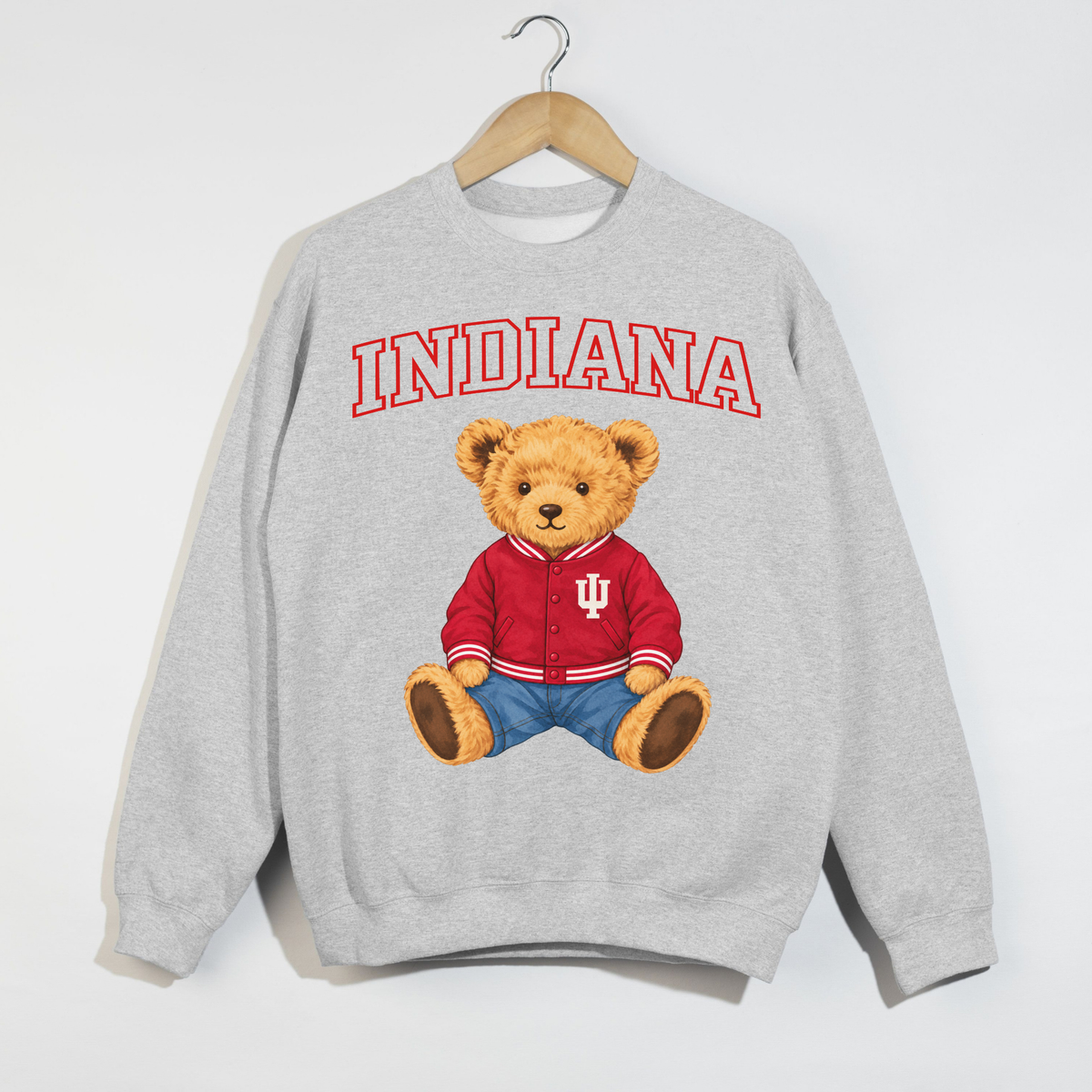 Ash grey Indiana teddy bear graphic sweatshirt displayed on a wooden hanger with red arched Indiana lettering and a teddy bear wearing a crimson collegiate jacket.
