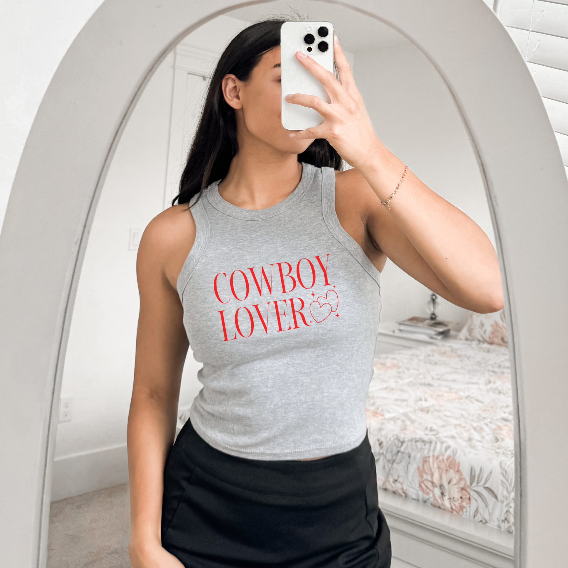 Woman wearing grey “Cowboy Lover” Bella + Canvas 1019 tank, taking mirror selfie in casual outfit.