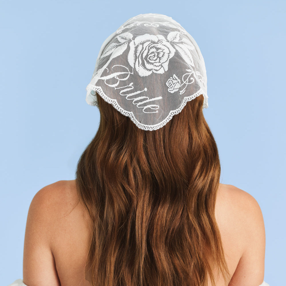 Person wearing a lace 'Bride' head covering against a light blue background