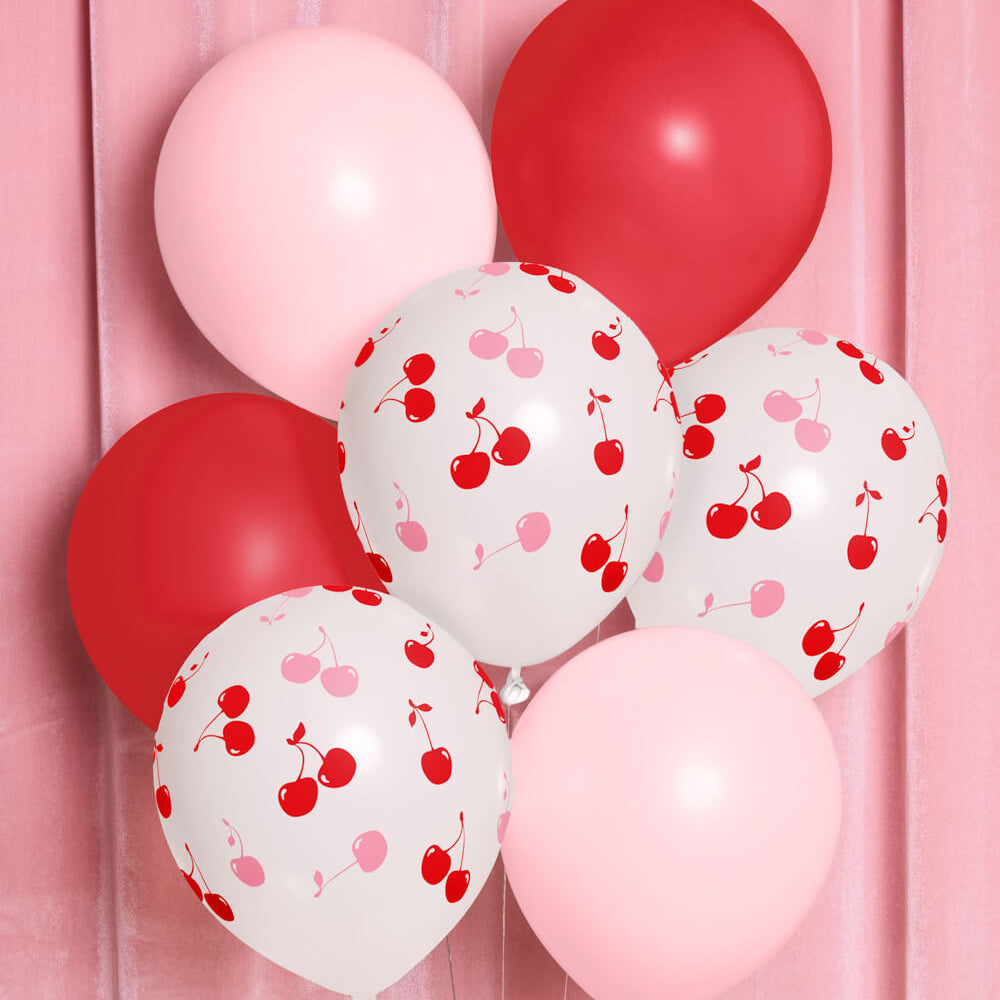 Red, pink, and white cherry print birthday balloons on pink backdrop