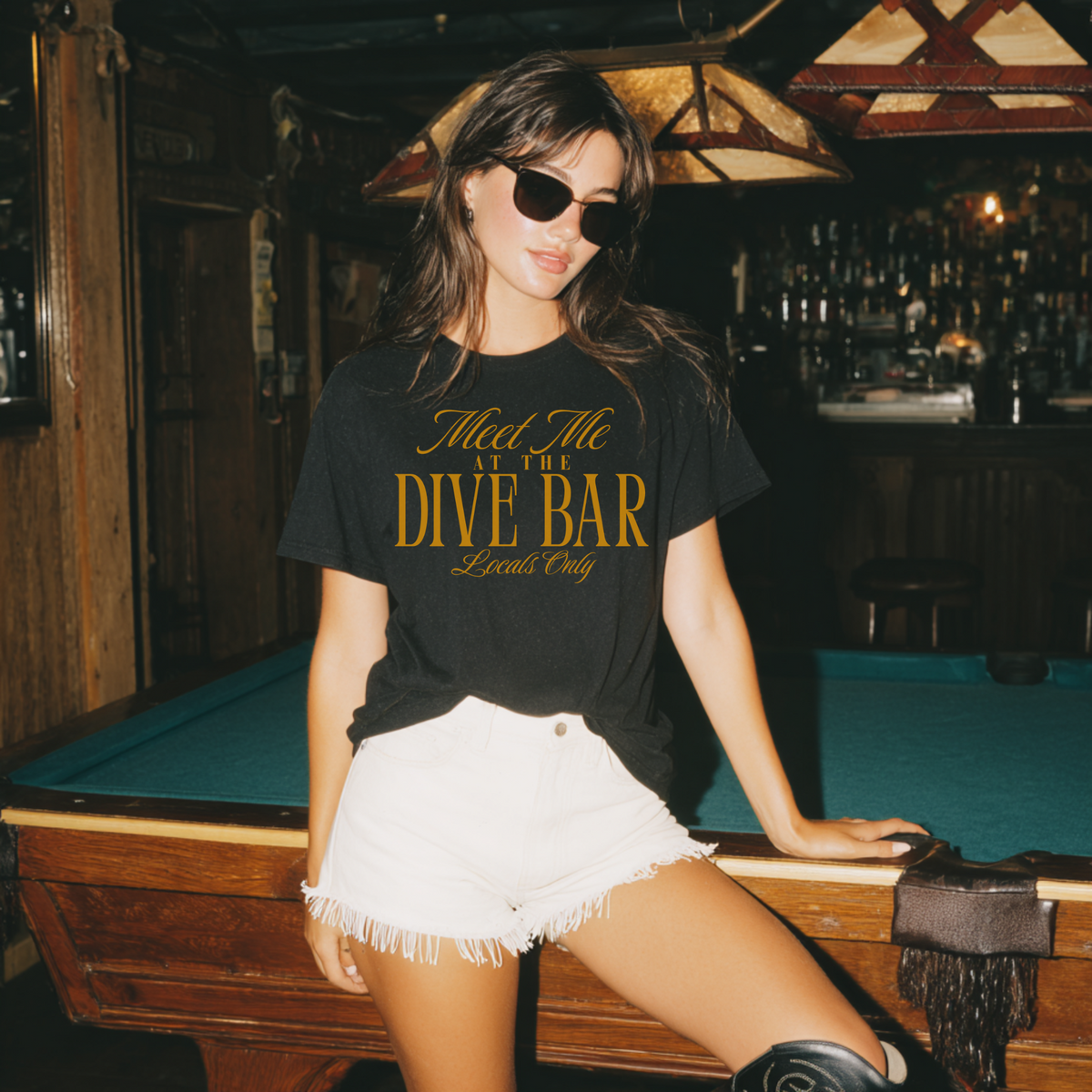 Woman wearing a black t-shirt with gold text in a bar setting