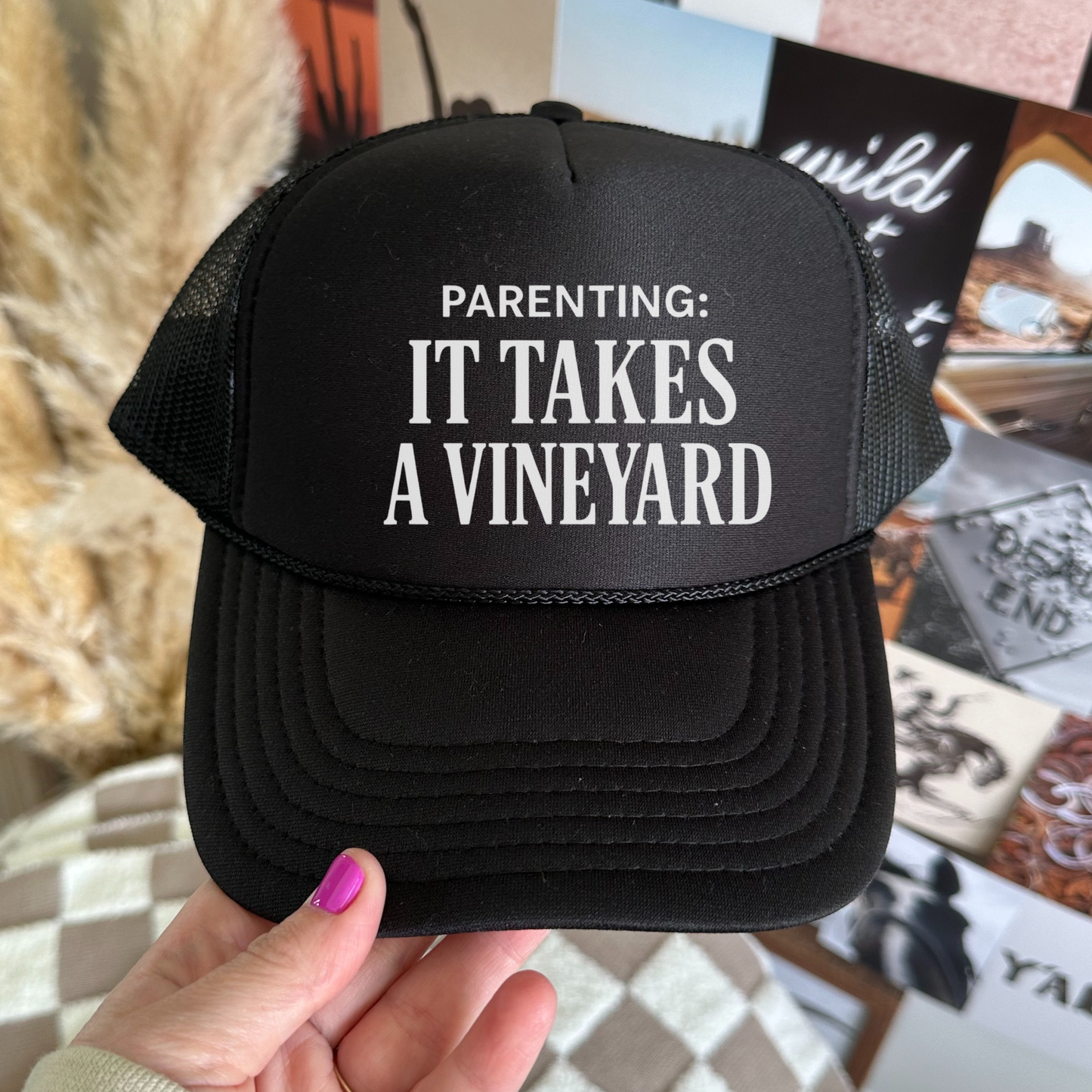Black trucker hat with white text reading “Parenting: It Takes a Vineyard” displayed close up