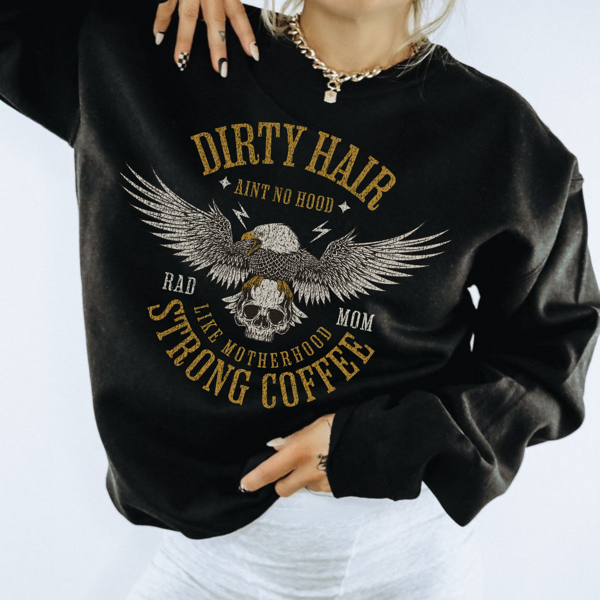 A person wearing a black sweatshirt with gold and white text that reads 'Dirty Hair Mom' and 'Strong Coffee', alongside an image of an eagle.
