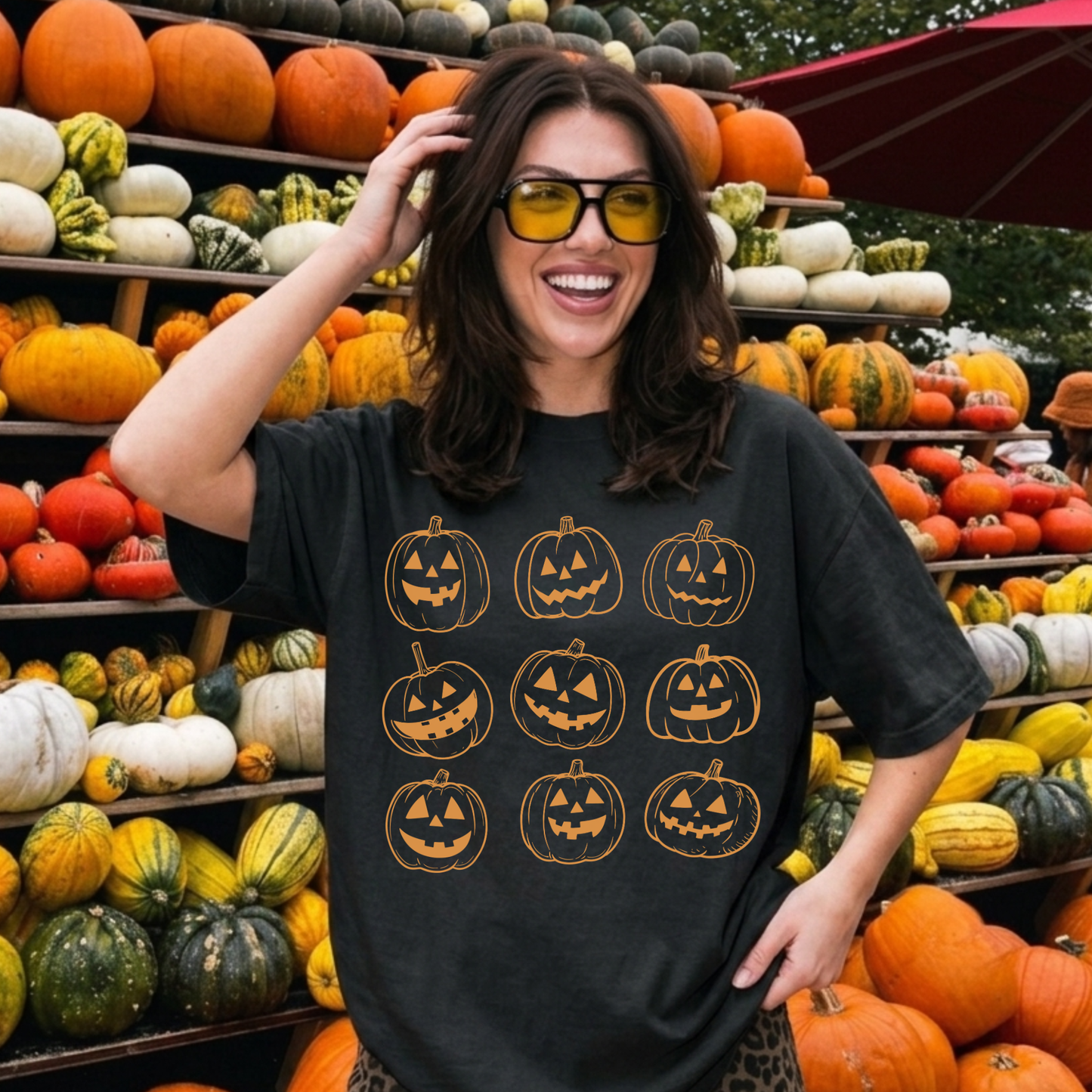 Woman wearing a black Comfort Colors Halloween pumpkin shirt featuring vintage orange jack o' lantern pumpkins at a festive pumpkin patch.