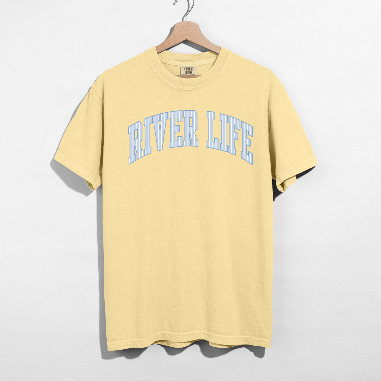 butter yellow river life graphic t shirt with blue collegiate lettering hanging on hanger product image