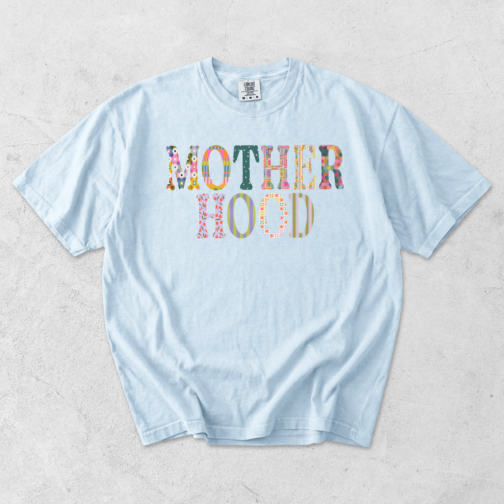 Chambray blue Comfort Colors motherhood graphic tee with colorful patterned motherhood graphic on front.
