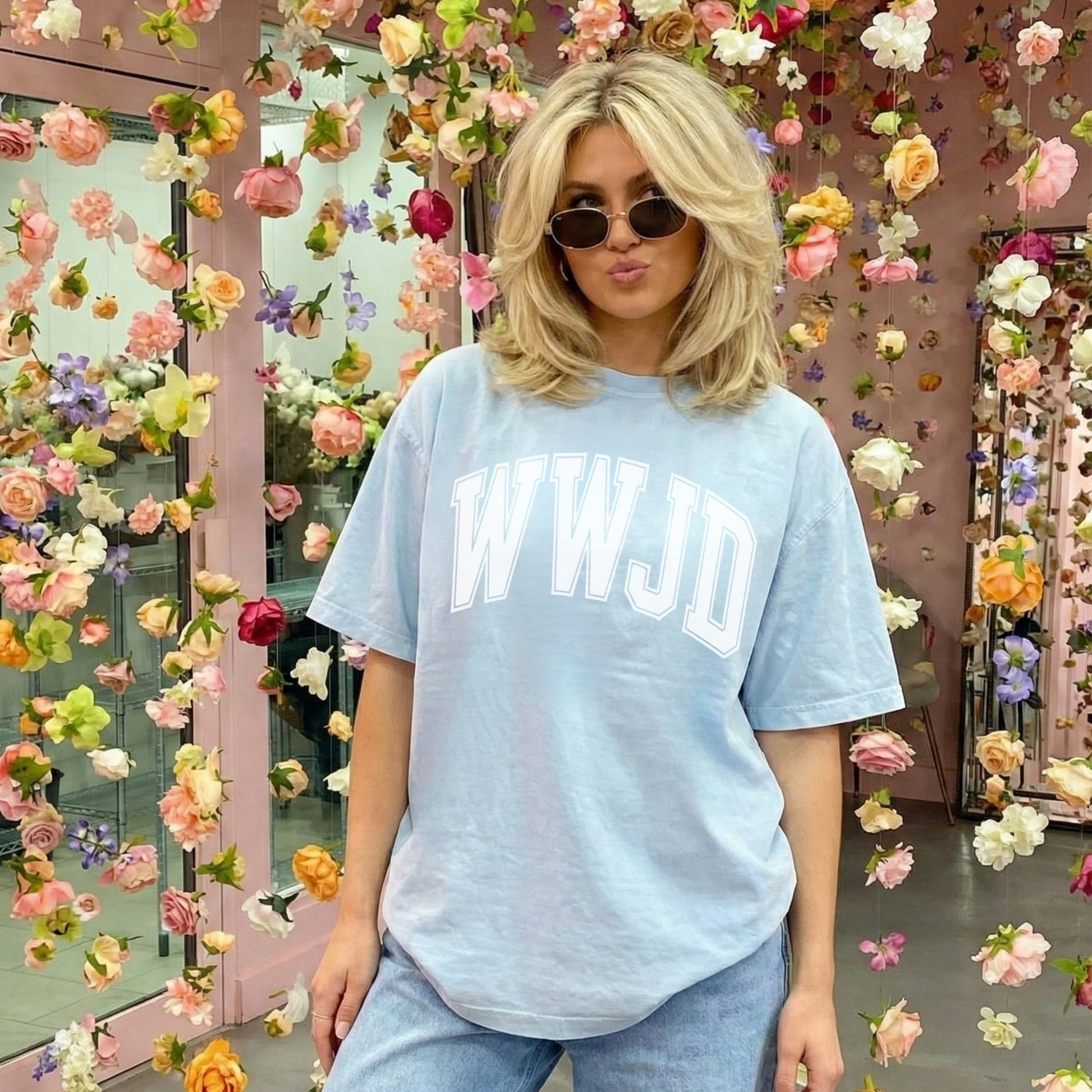 Woman wearing a light blue t-shirt with 'WWJD' text in front of a floral background