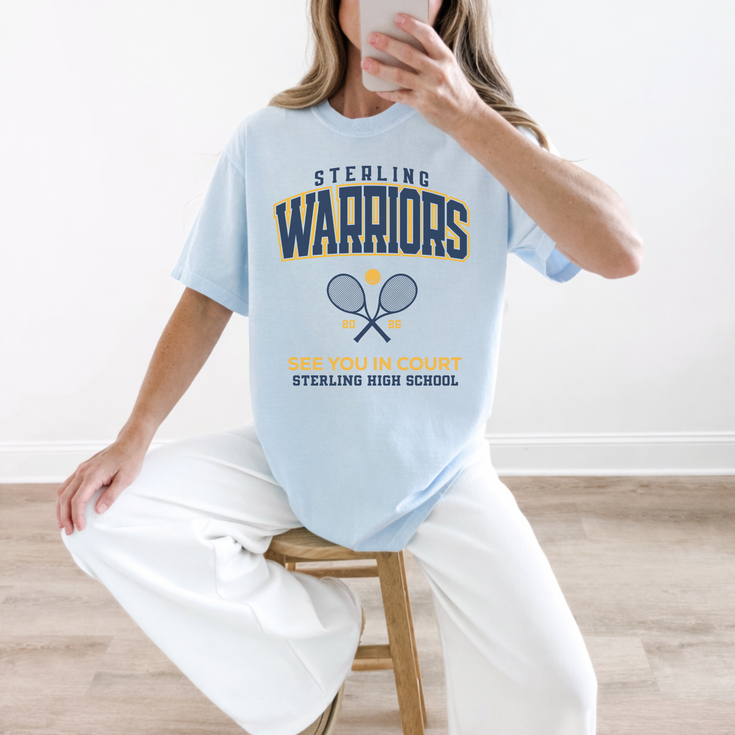 Woman wearing a chambray Sterling Warriors Tennis graphic t-shirt with “See You in Court” lettering