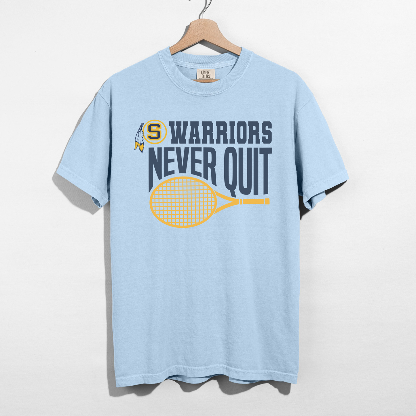 Light blue t-shirt with 'Warriors Never Quit' graphic on a hanger against a white background