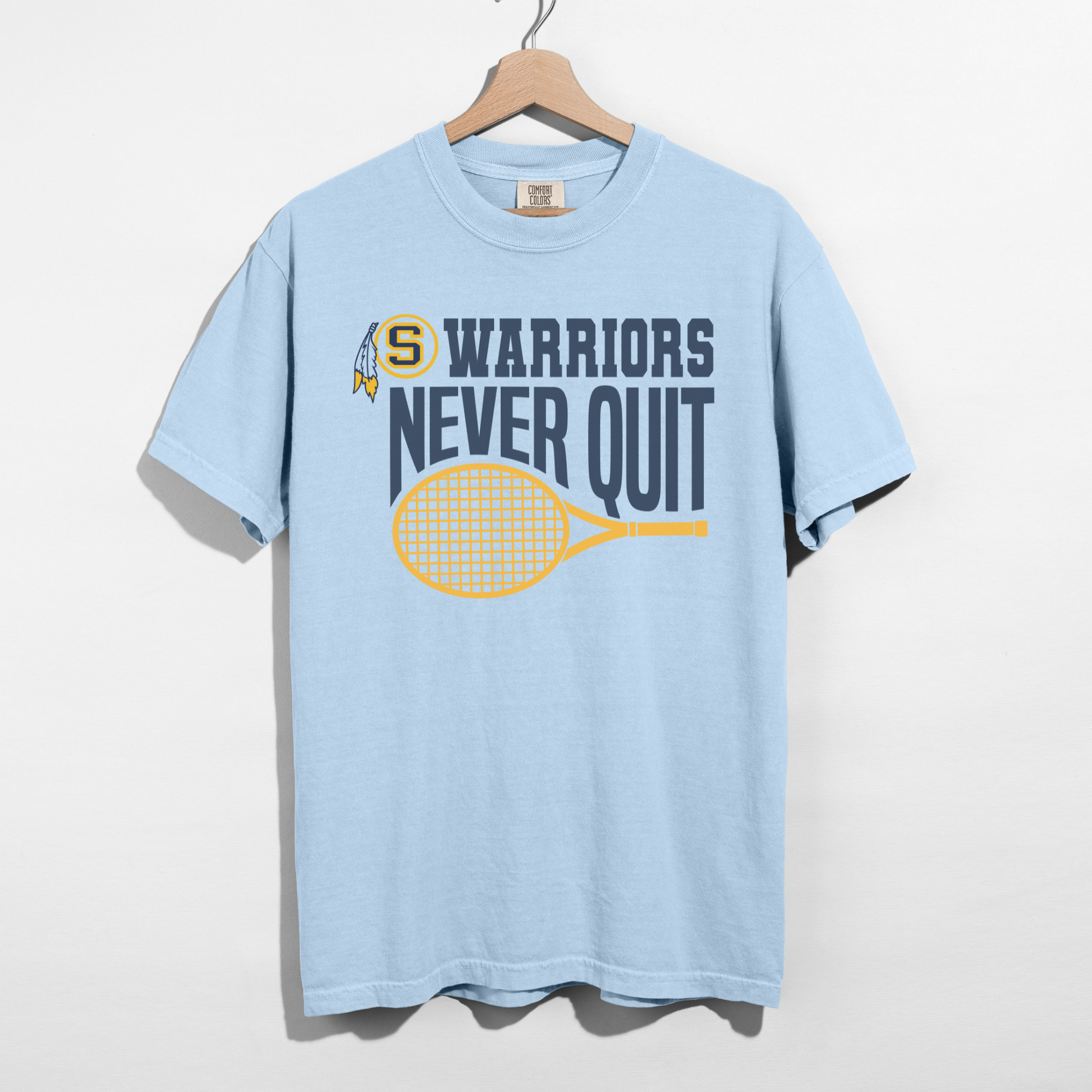 Light blue t-shirt with 'Warriors Never Quit' graphic on a hanger against a white background