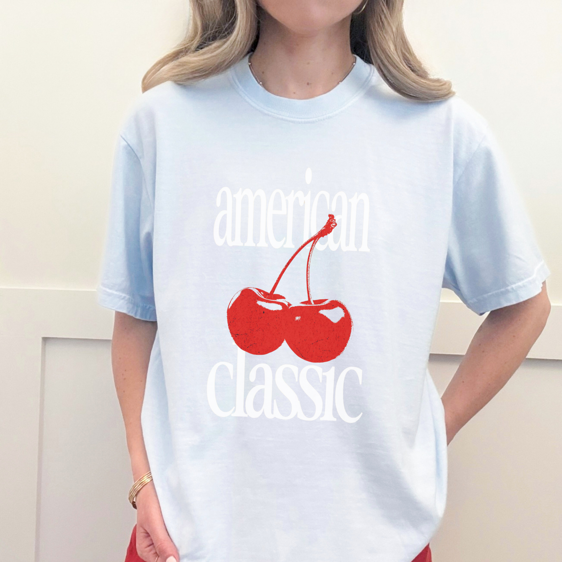 Woman wearing chambray blue ‘American Classic’ tee with red cherries and white vintage font
