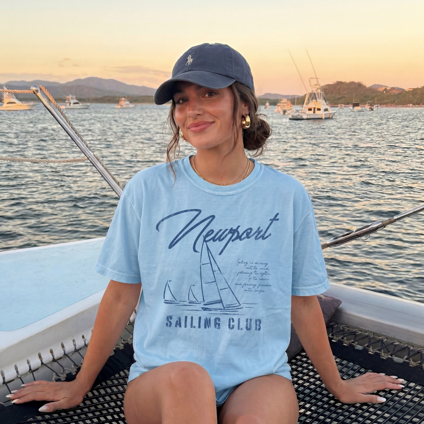 woman wearing blue sailing club graphic t shirt on boat preppy coastal outfit aesthetic