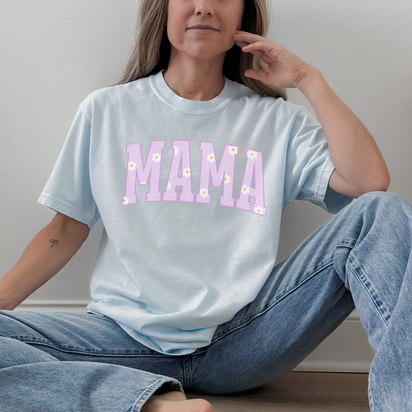Woman wearing a light blue Comfort Colors mama graphic t-shirt with pastel purple daisy lettering, relaxed everyday style