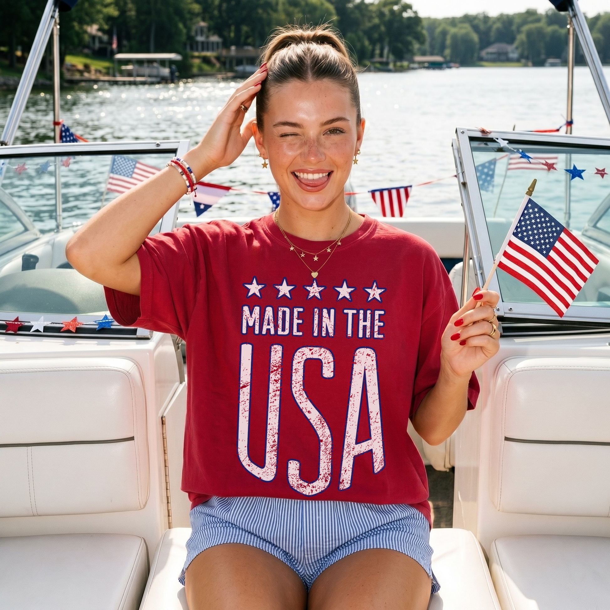 Woman wearing red Made in the USA graphic t-shirt on a boat holding American flag patriotic summer outfit