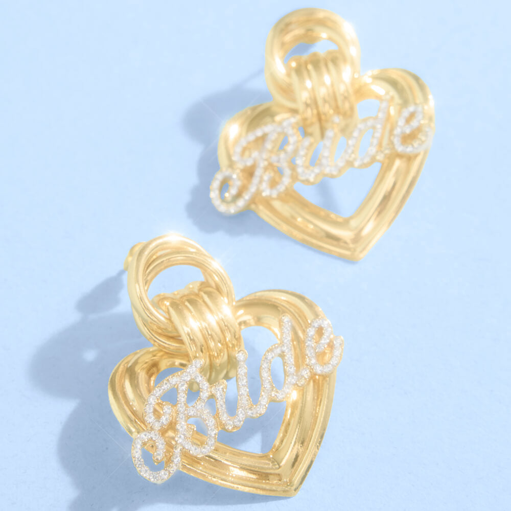 Close up of gold metal heart bridal earrings with crystal rhinestone script