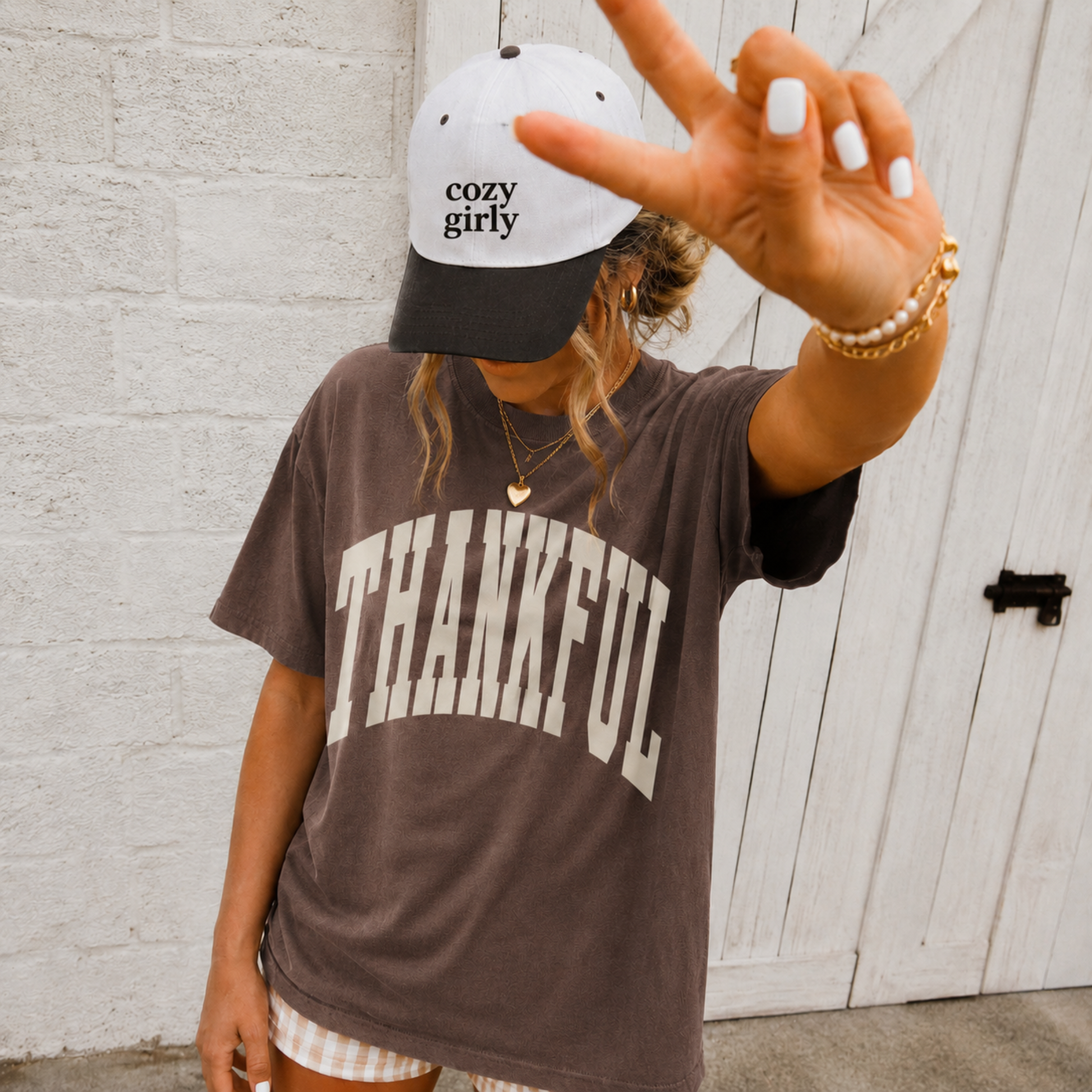 Woman wearing espresso brown Thankful graphic tee with oversized cream collegiate lettering and fall accessories