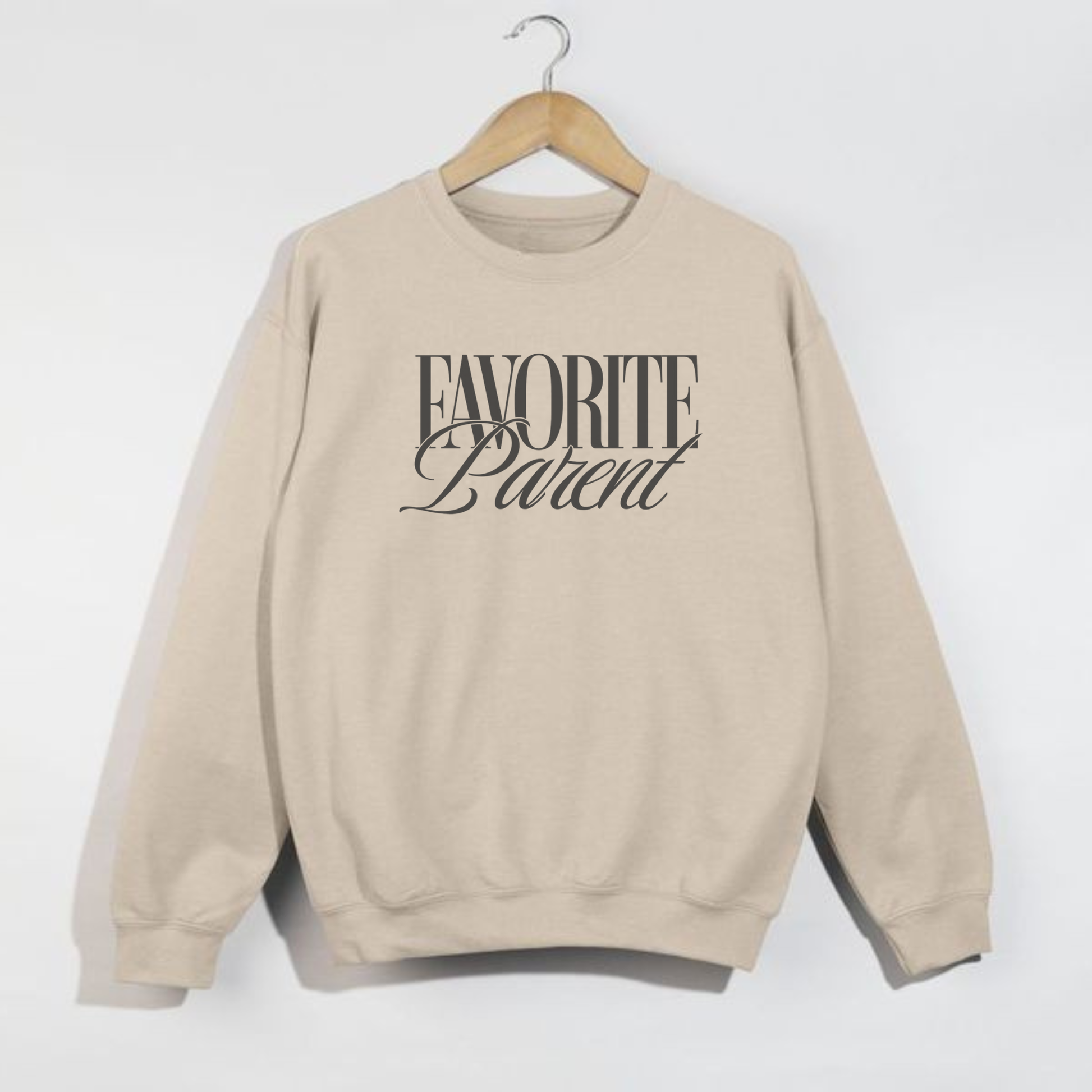 Sand Favorite Parent crewneck sweatshirt with black lettering hanging on wooden hanger against white wall