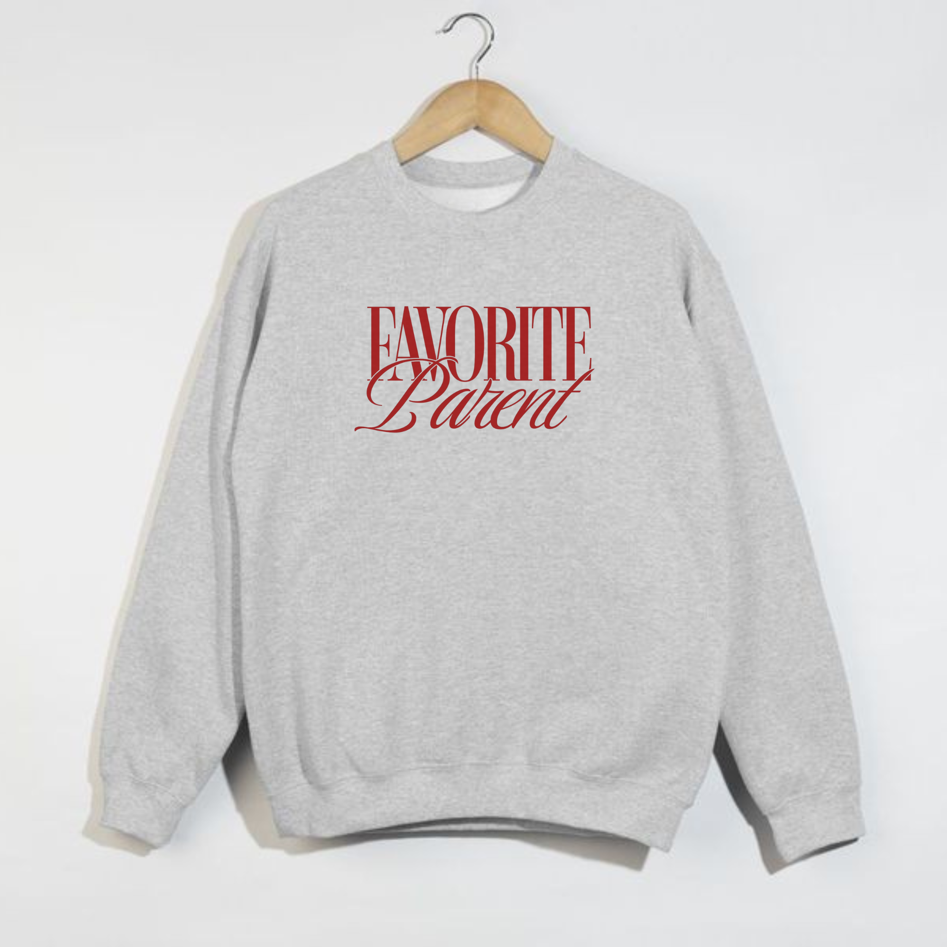 Ash grey Favorite Parent crewneck sweatshirt with red text hanging on wooden hanger against white wal