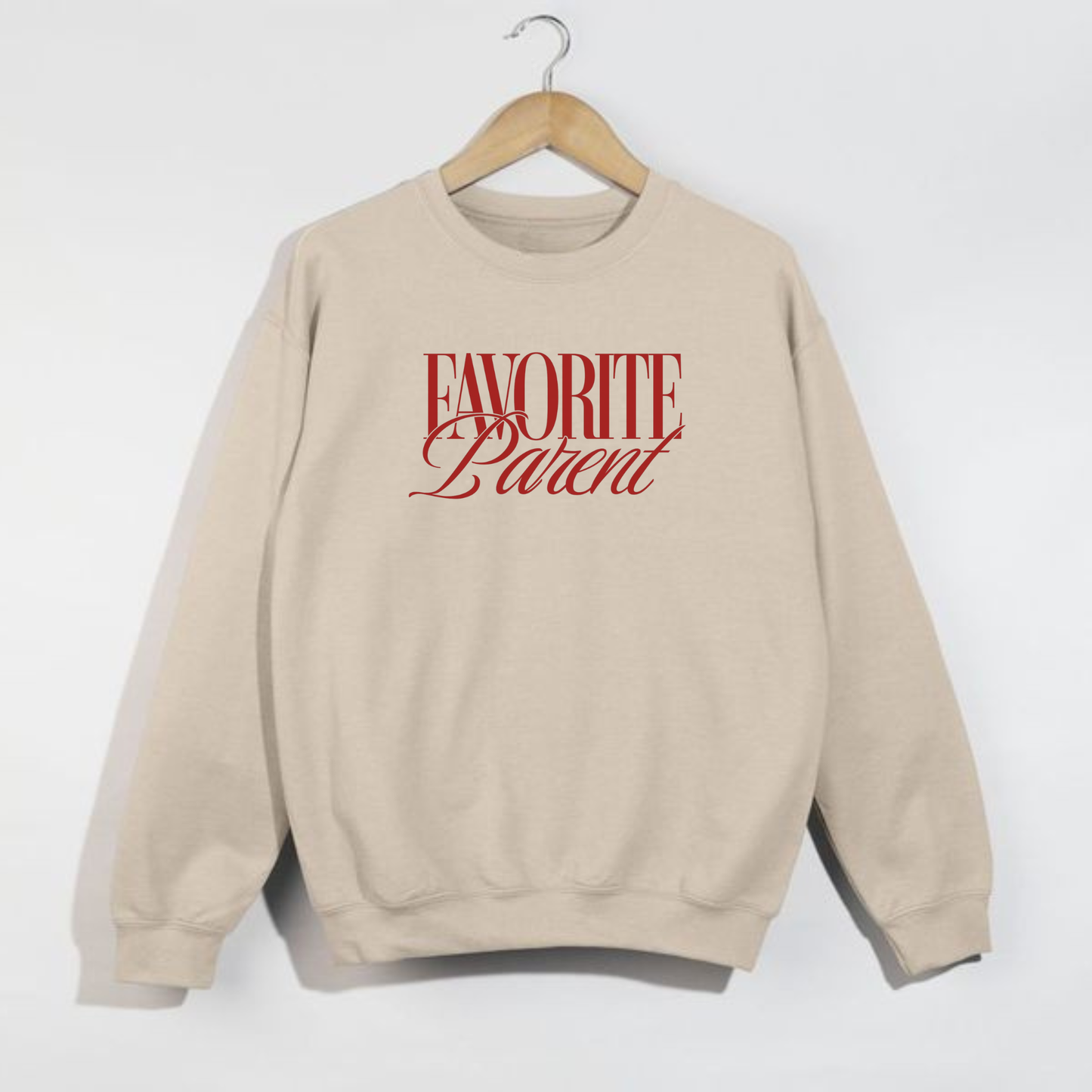 Sand Favorite Parent sweatshirt with red lettering hanging on wooden hanger against white background