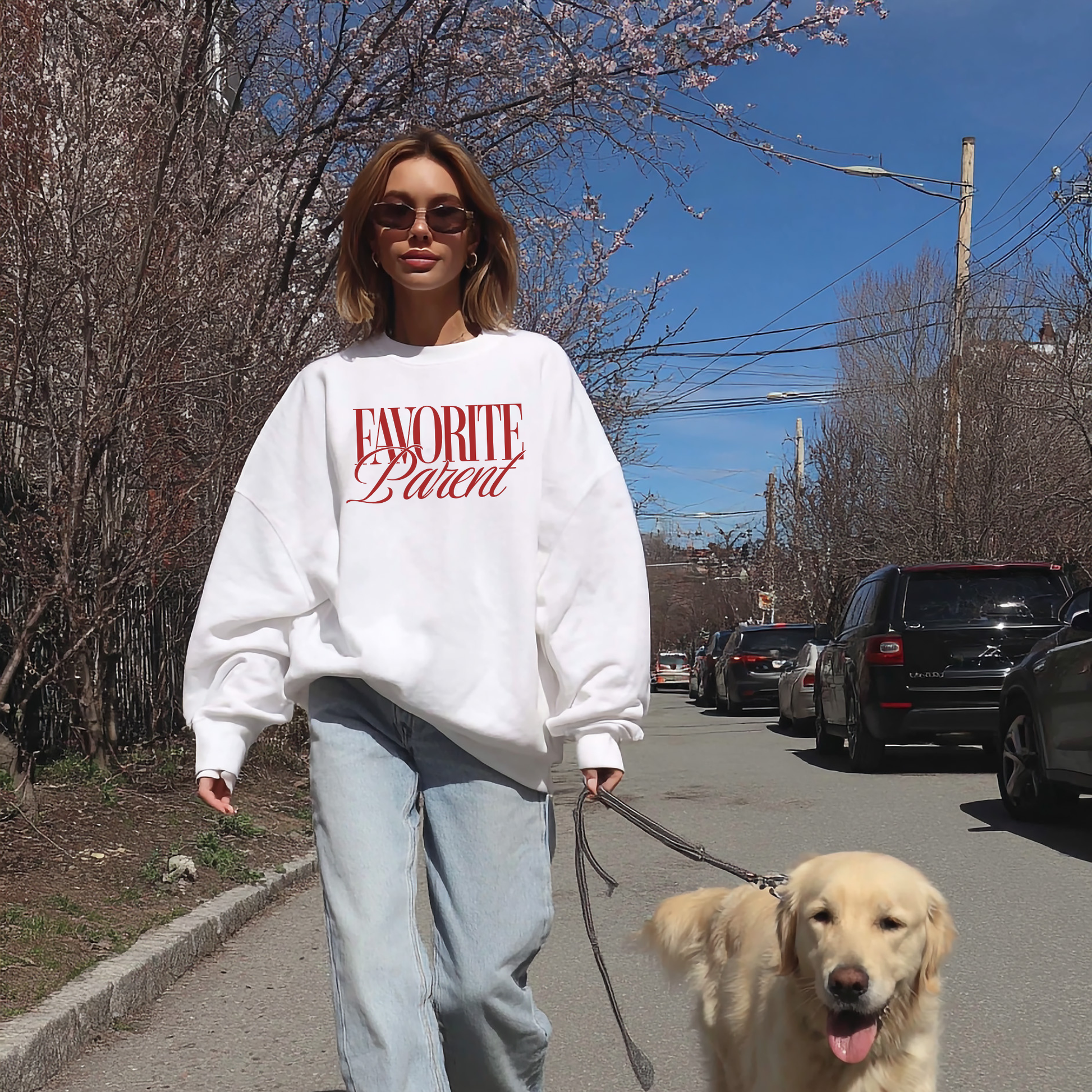 White Favorite Parent sweatshirt with red print worn by woman walking dog on sunny day