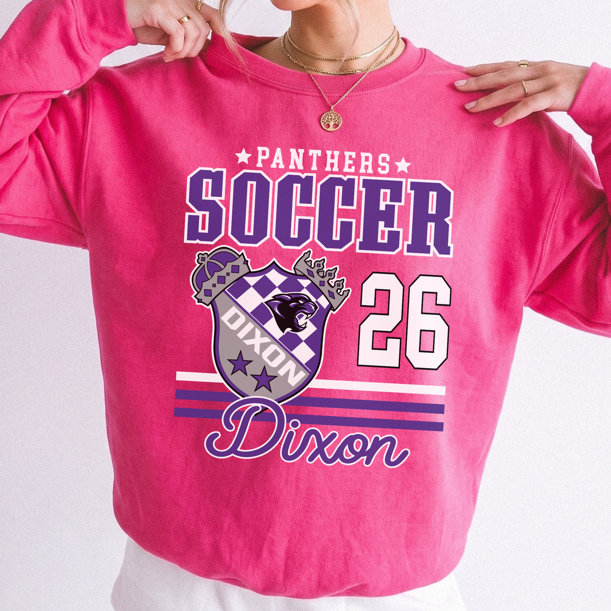 Woman wearing a bright pink Dixon Panthers Soccer 2026 sweatshirt with purple varsity lettering and Panthers crest graphic.
