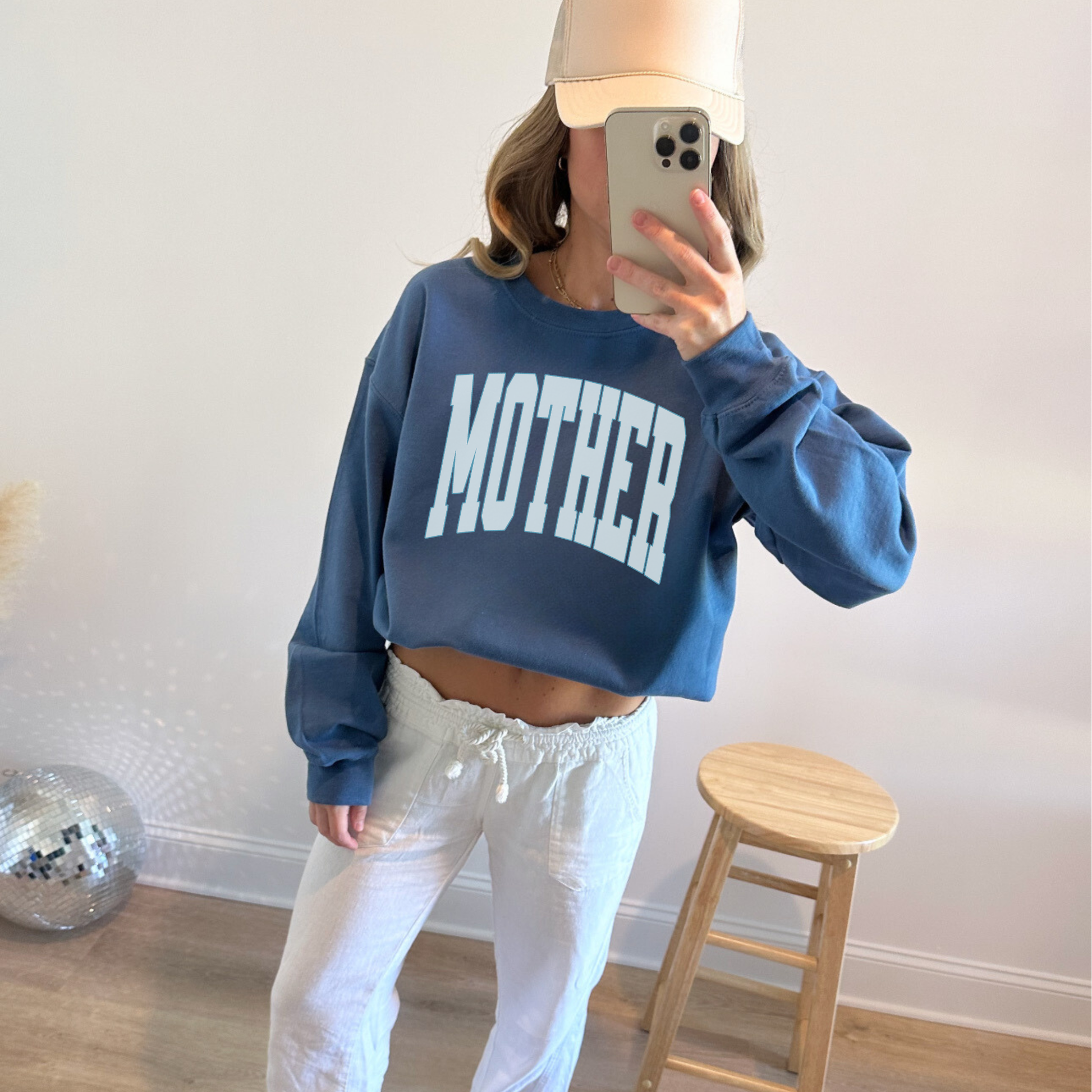 Blue cropped MOTHER sweatshirt styled with white pants and baseball cap