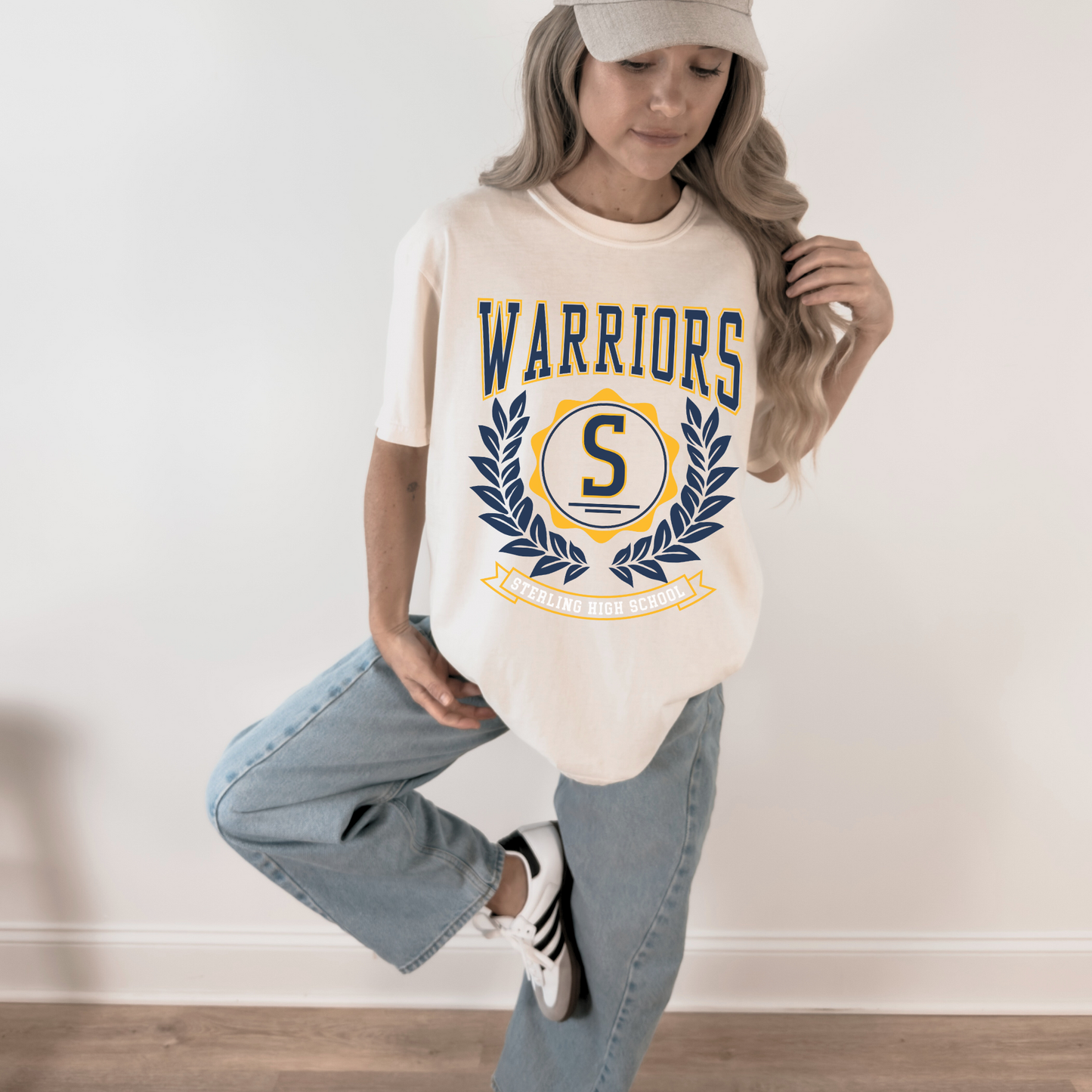Person wearing a 'Warriors' t-shirt with a logo, standing against a plain background