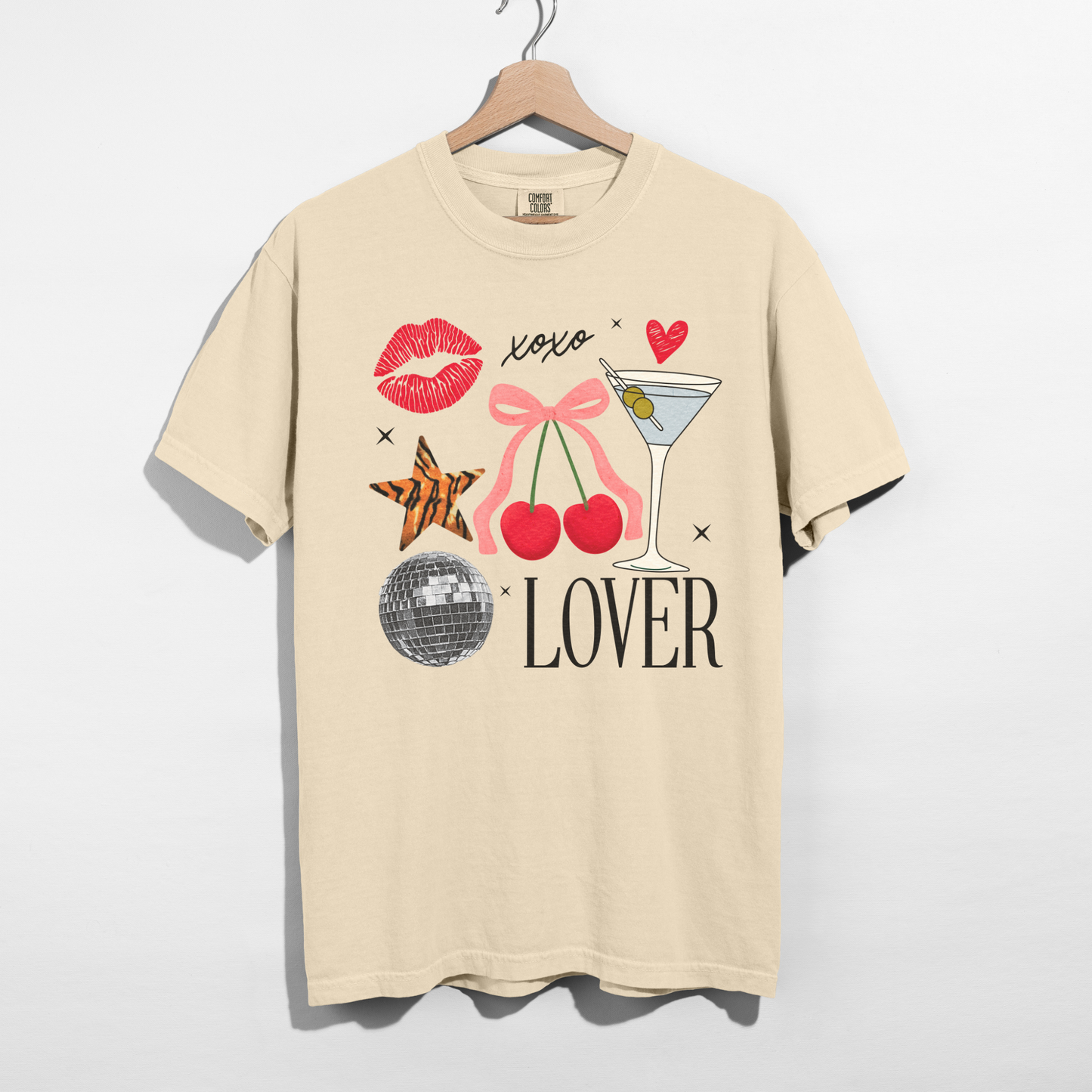 Ivory Lover graphic t-shirt with cherry, martini glass, and bow design displayed on wooden hanger.