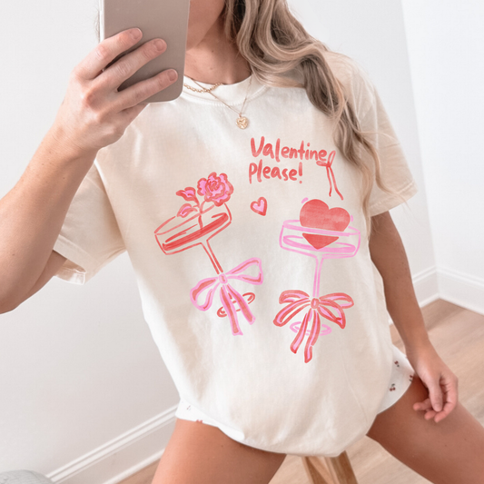 Woman wearing ivory Valentine Please tee with pink hand-drawn graphic, mirror selfie.