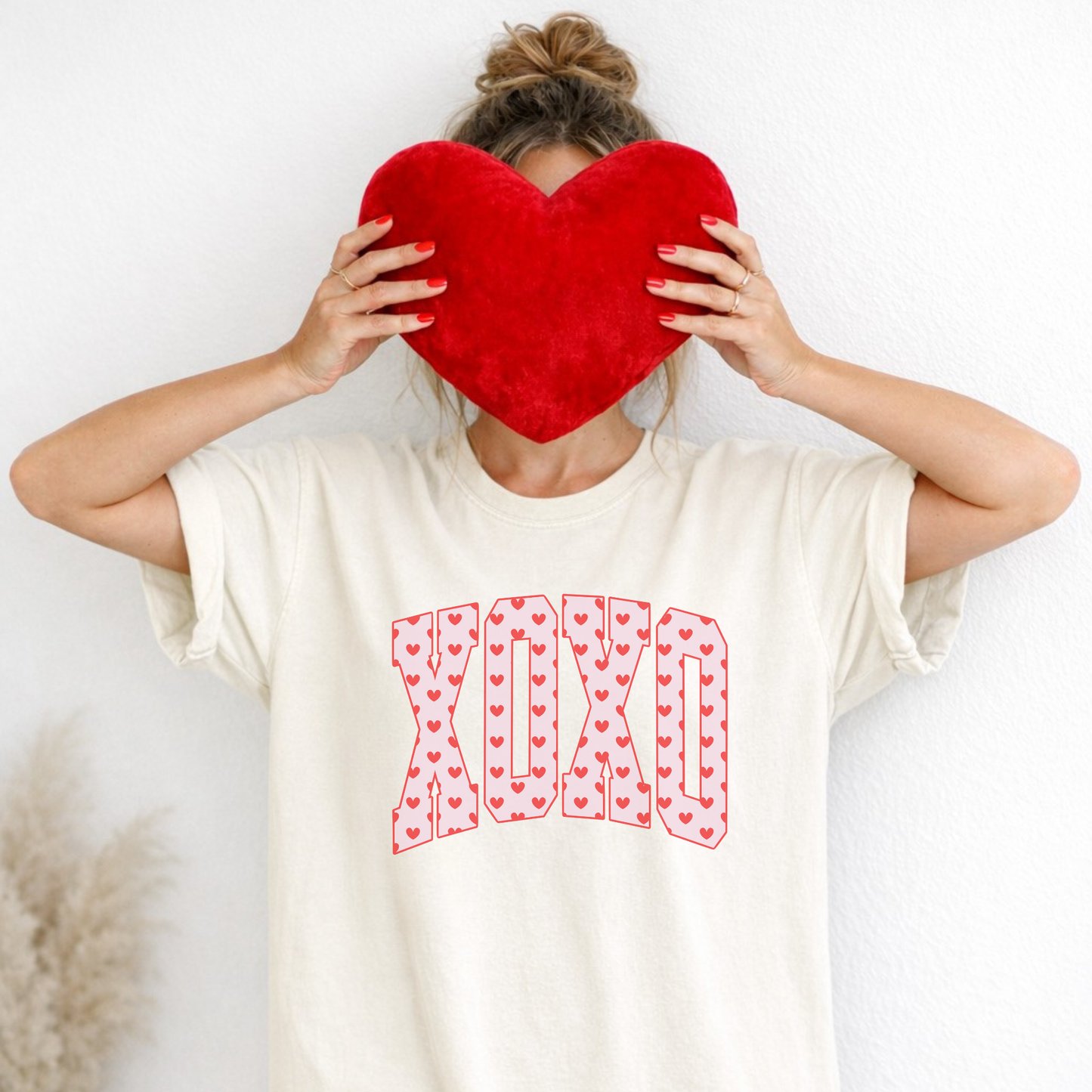 Model holding red heart pillow wearing ivory XO heart print Comfort Colors tee