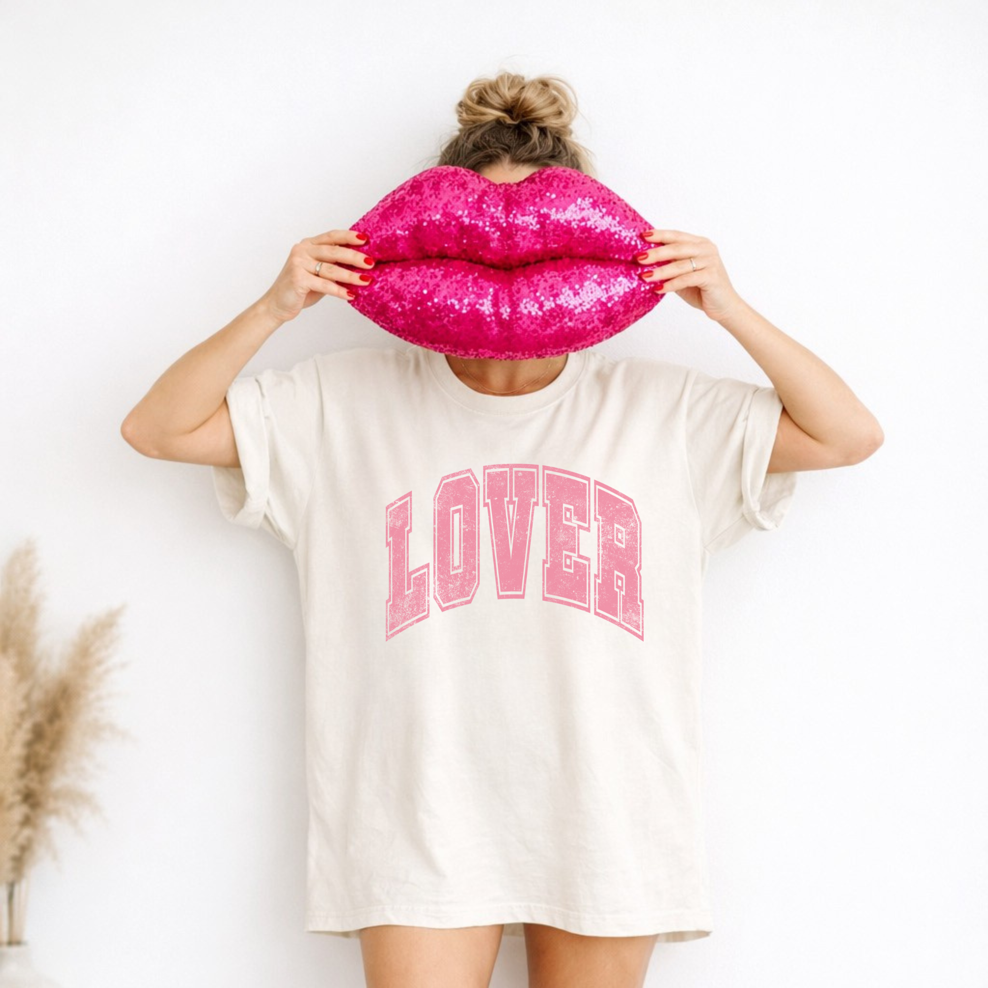 Model wearing ivory Lover graphic tee holding pink lips pillow