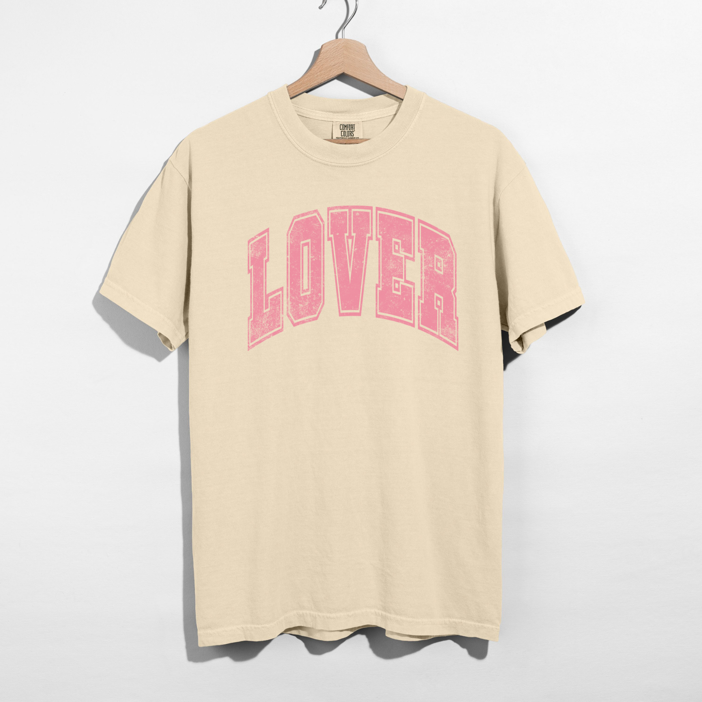 Ivory Comfort Colors Lover graphic tee flat lay showing pink collegiate lettering