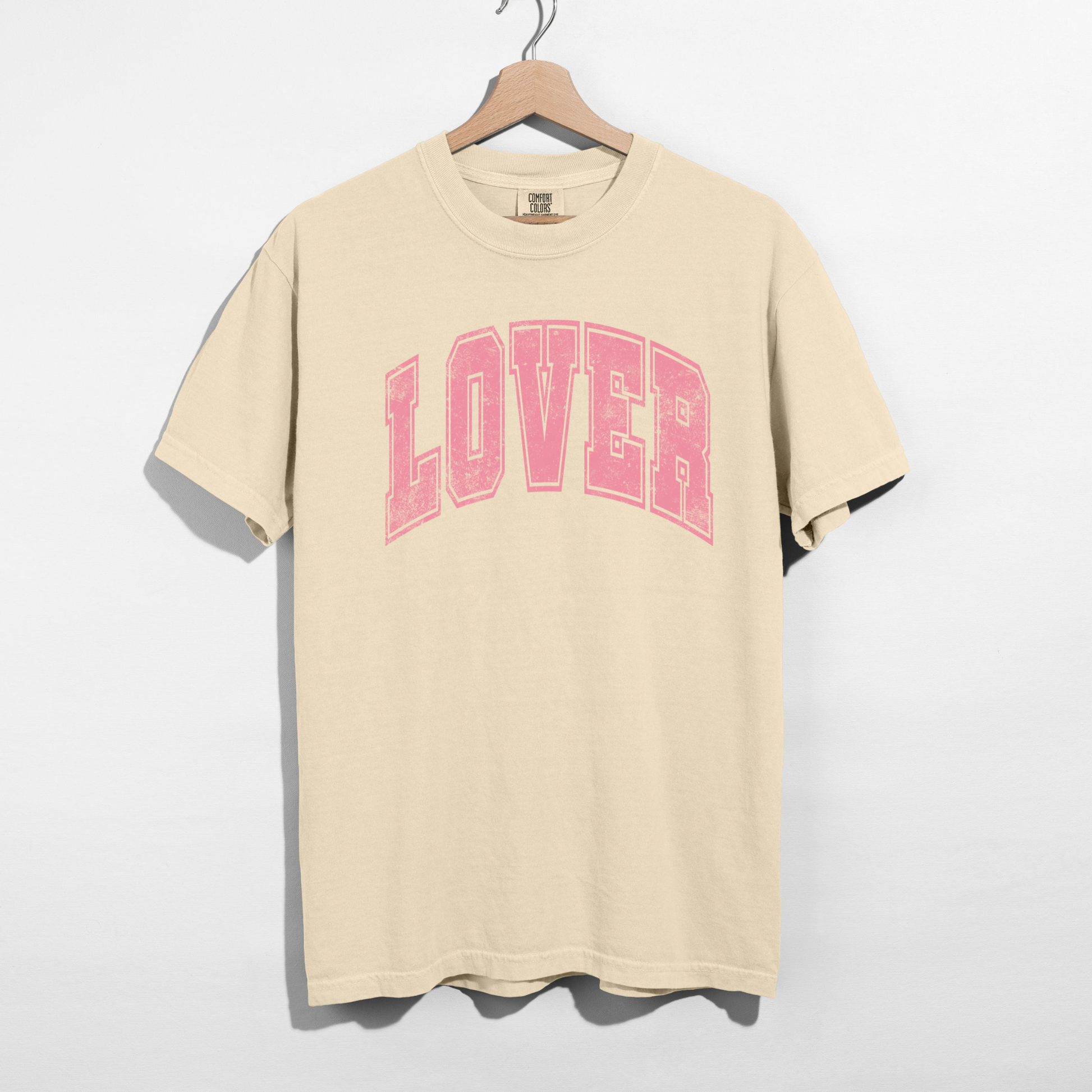 Ivory Comfort Colors Lover graphic tee flat lay showing pink collegiate lettering
