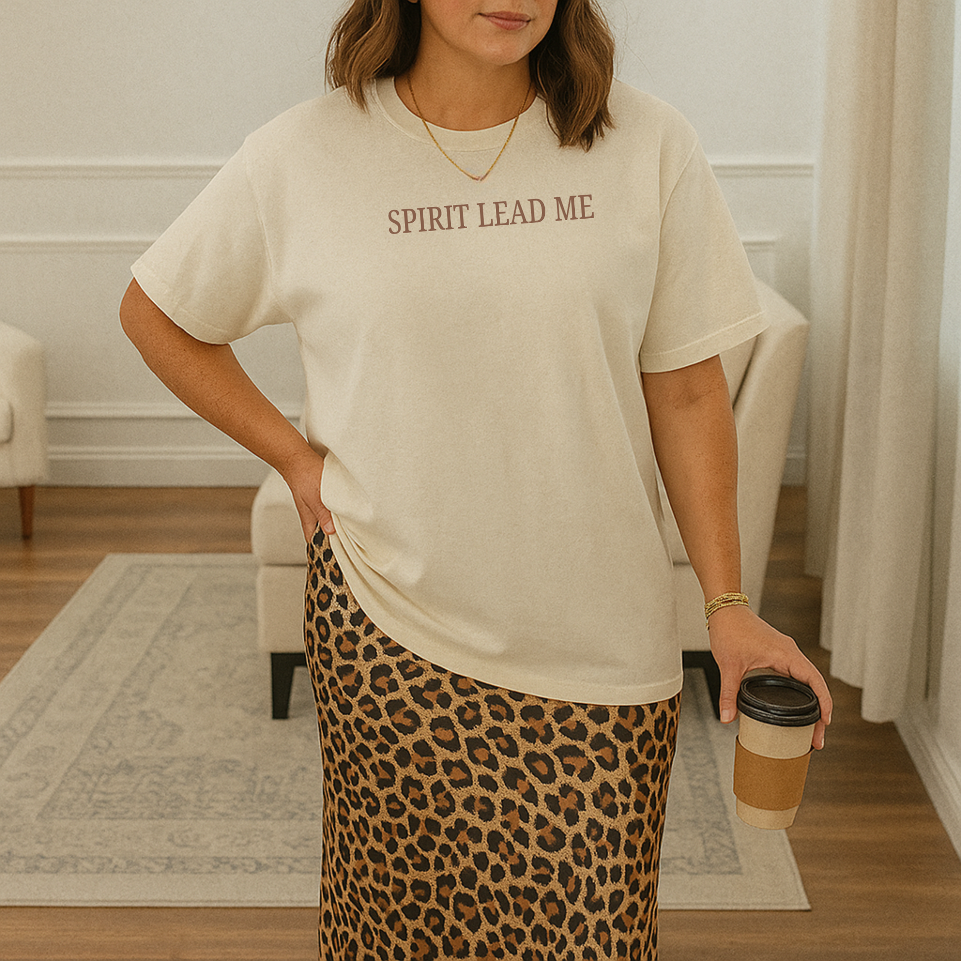 Woman wearing ivory Spirit Lead Me Christian graphic tee styled with leopard skirt and neutral home decor