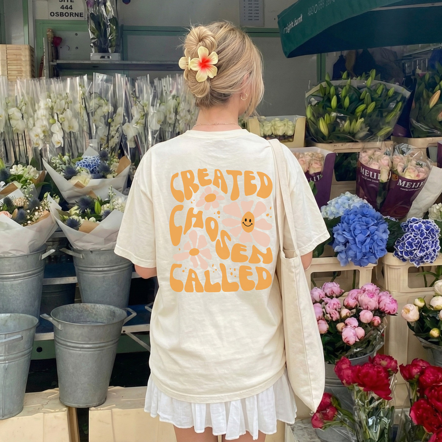 Person wearing a white t-shirt with text and flowers in a flower shop