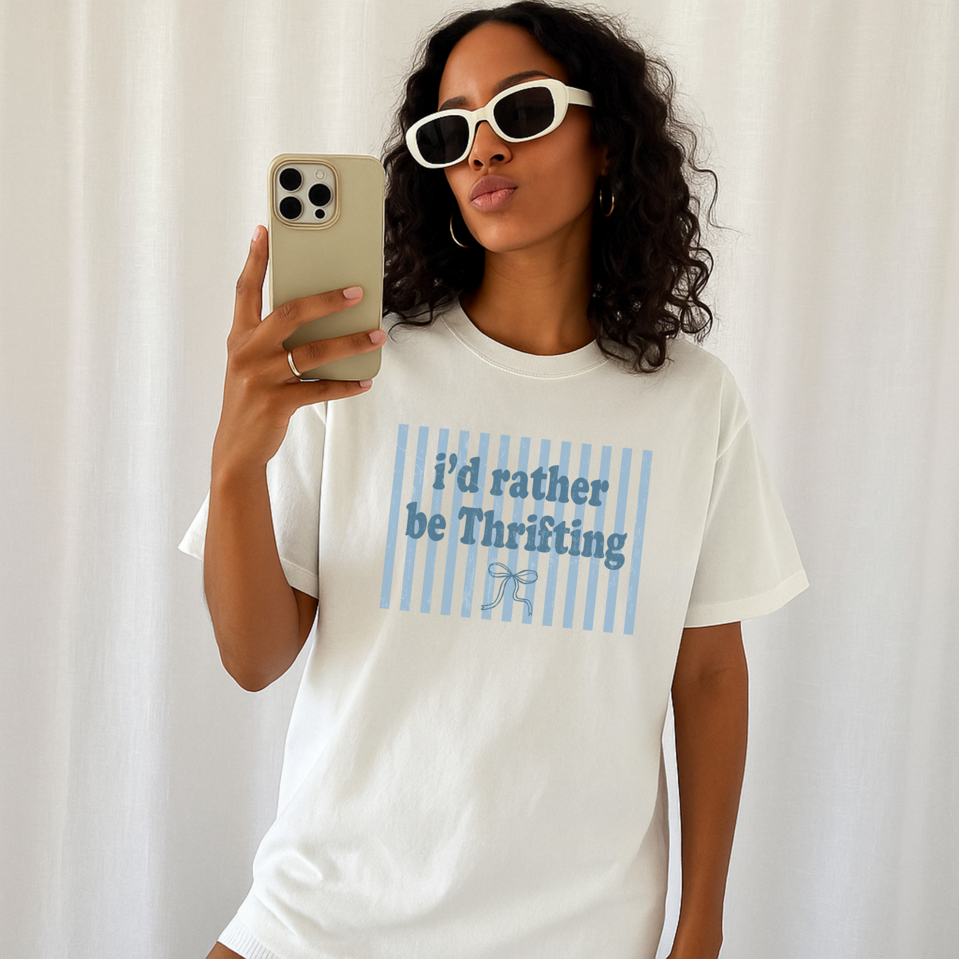 Woman wearing ivory “I’d Rather Be Thrifting” graphic tee styled casually indoors