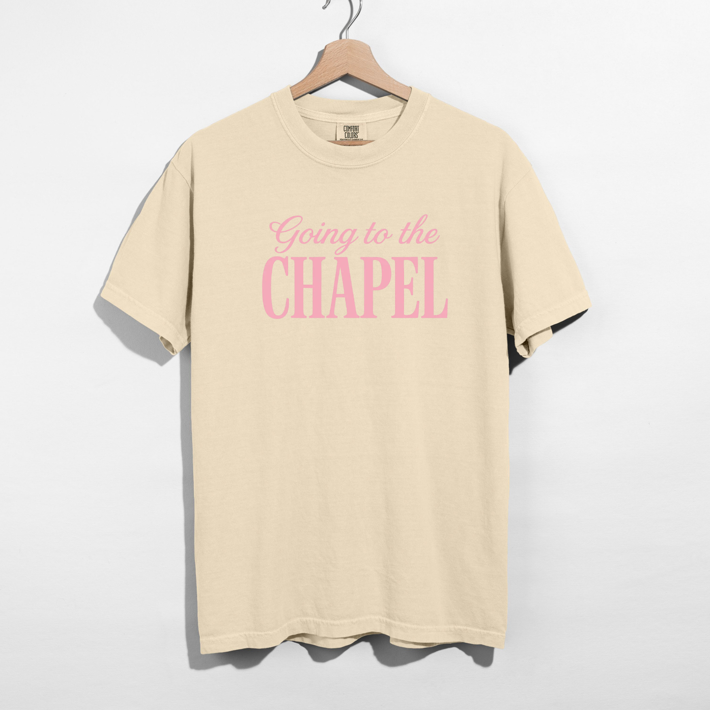 Ivory Comfort Colors t-shirt with pink “Going to the Chapel” bridal graphic on hanger