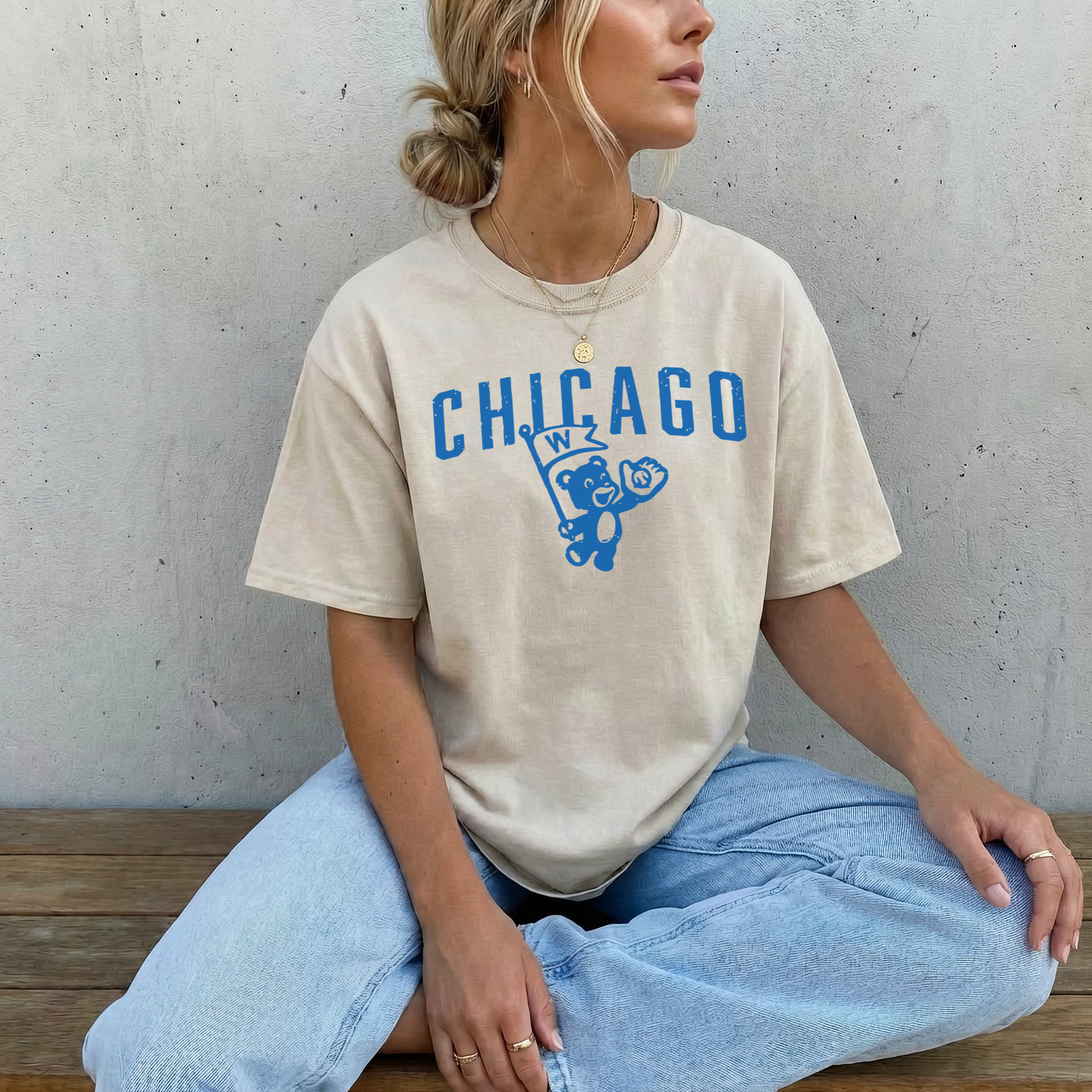 Woman wearing ivory Chicago vintage cub graphic t-shirt styled with light wash jeans against textured neutral wall.