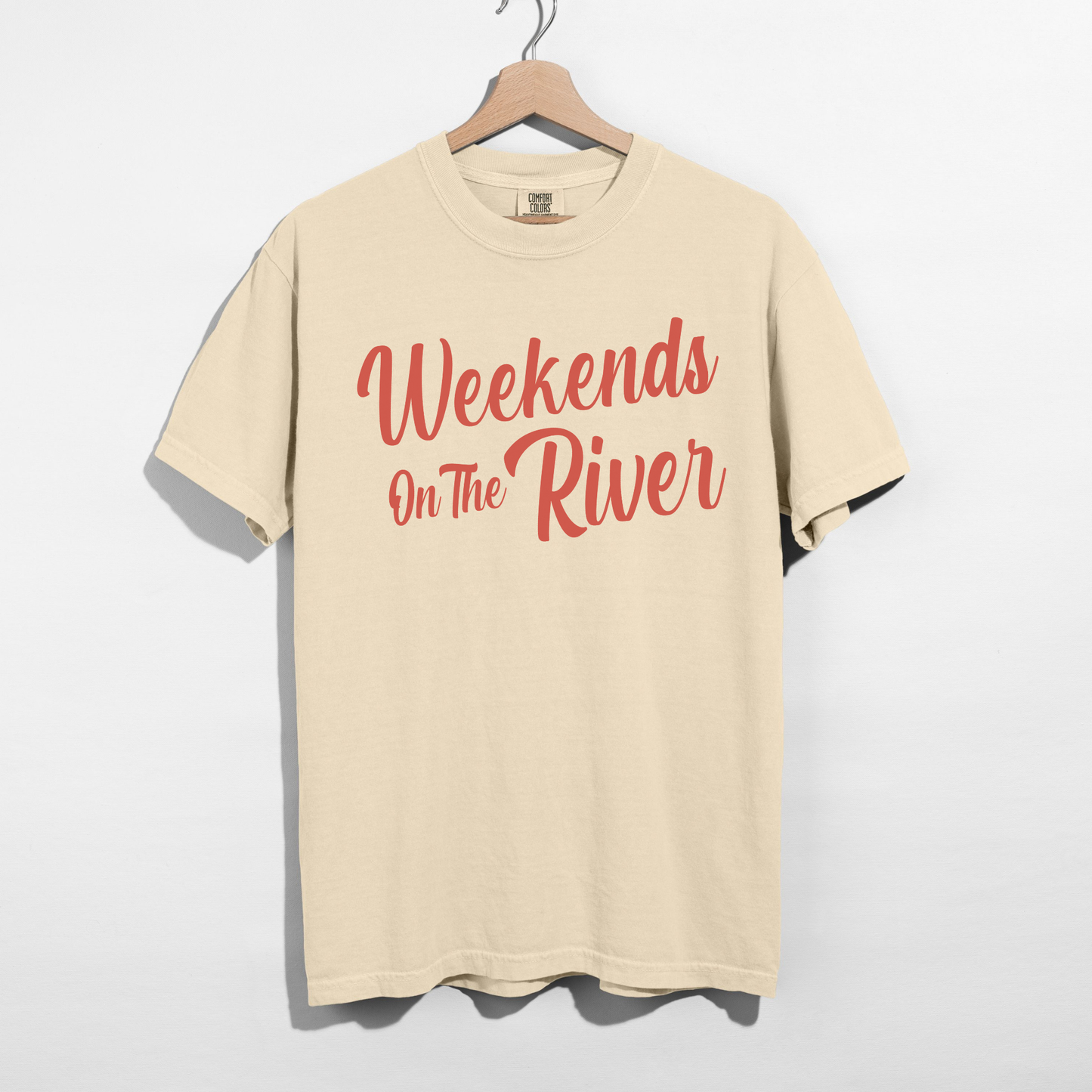 Ivory Comfort Colors summer graphic tee with coral red “Weekends On The River” script design on front.