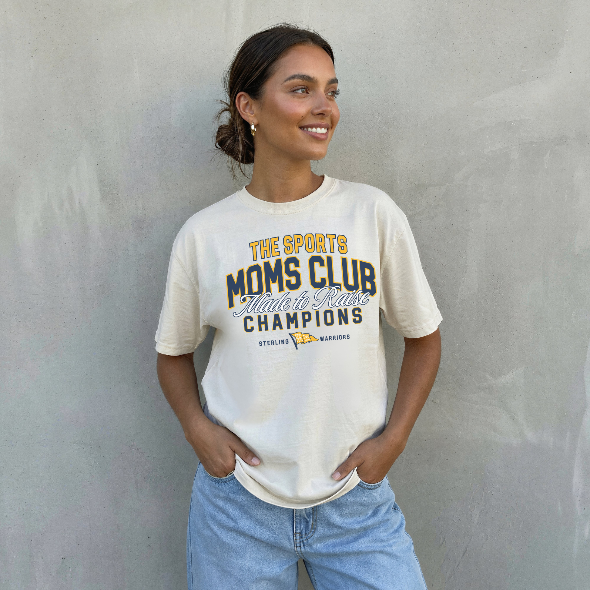 sports moms club sterling warriors ivory t-shirt worn by woman with jeans casual neutral game day outfit