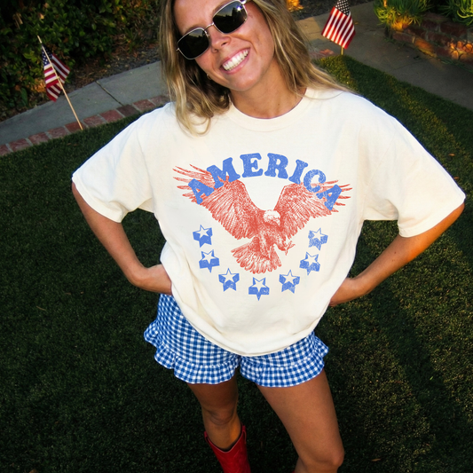 Ivory vintage patriotic t-shirt styled with blue gingham shorts and boots