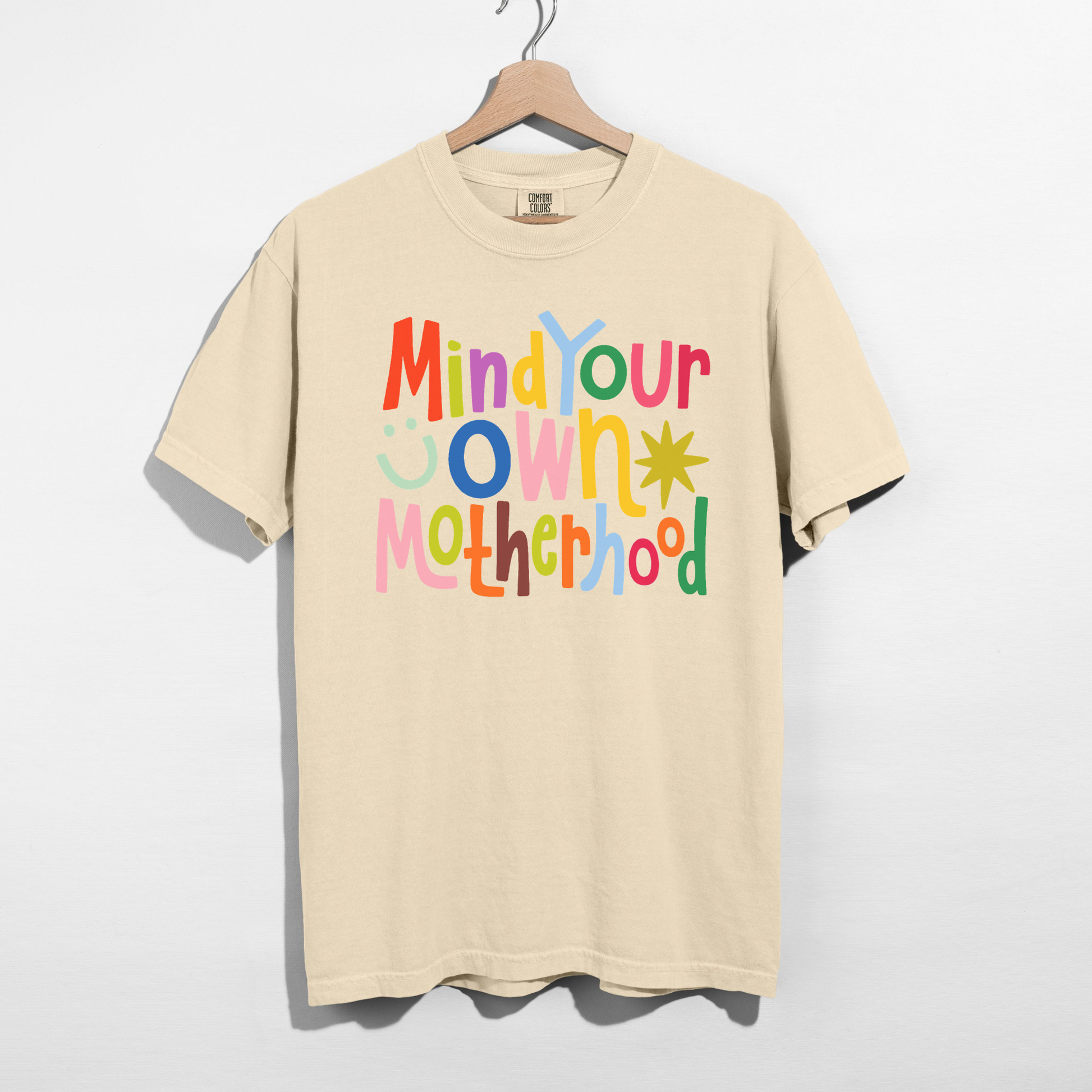 Retro colorful Mind Your Own Motherhood motherhood graphic tee on ivory Comfort Colors shirt flat lay mockup